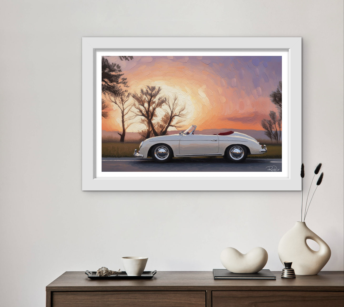 Framed artwork of a classic car at sunset on a wall above a wooden console table with decorative items.