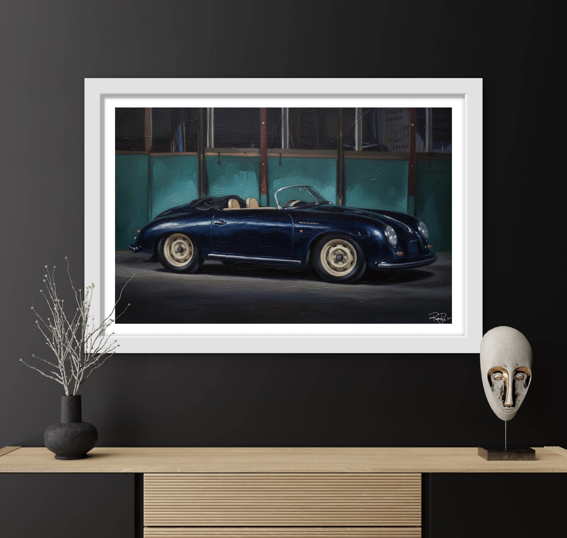 Framed artwork of a vintage car on a dark wall with decorative items below.