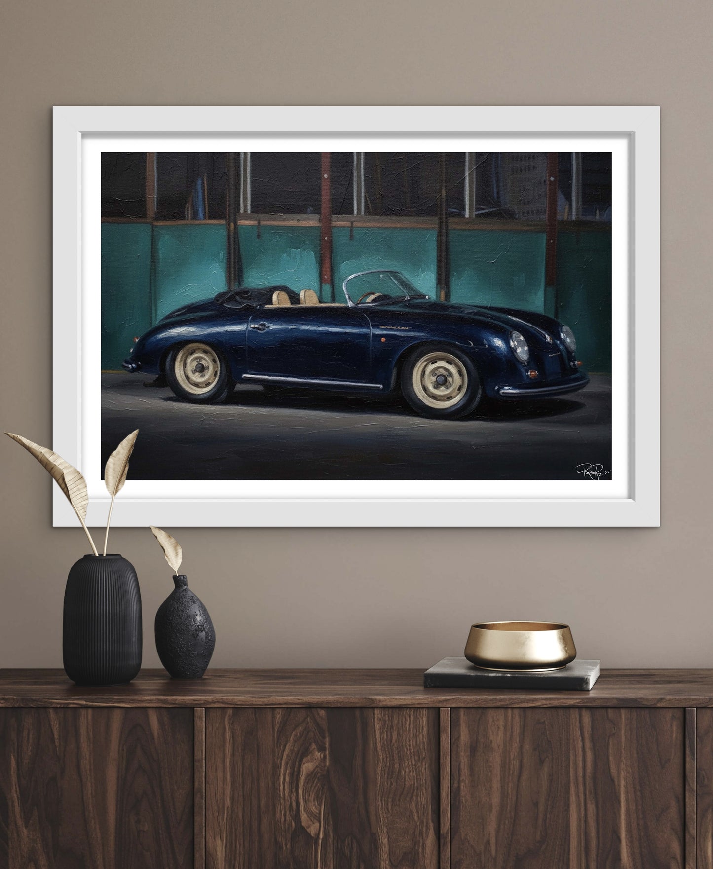 Framed artwork of a classic car on a wall above a wooden console table.