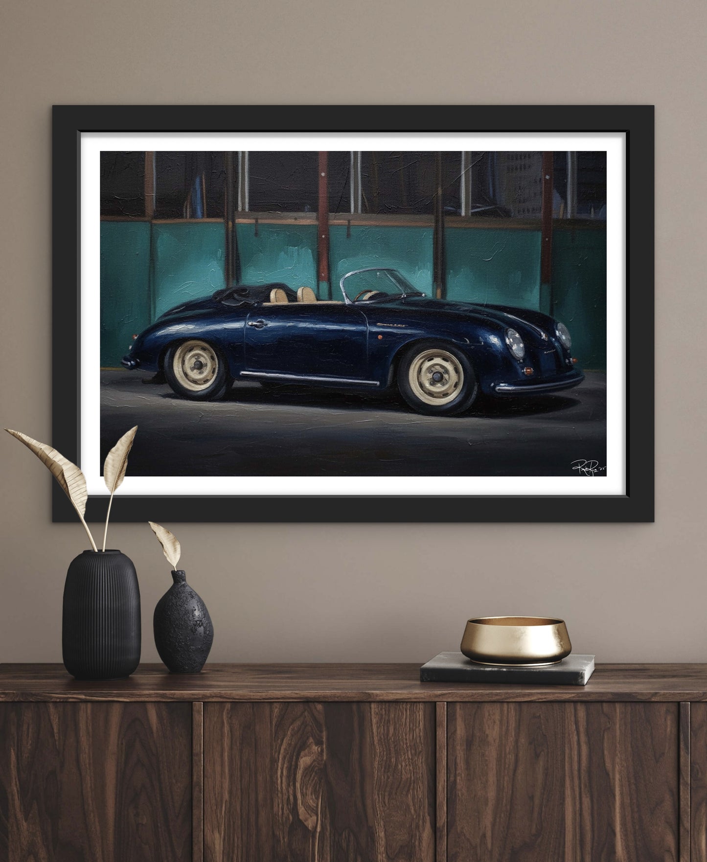 Framed artwork of a vintage car on a wall above a wooden console table.