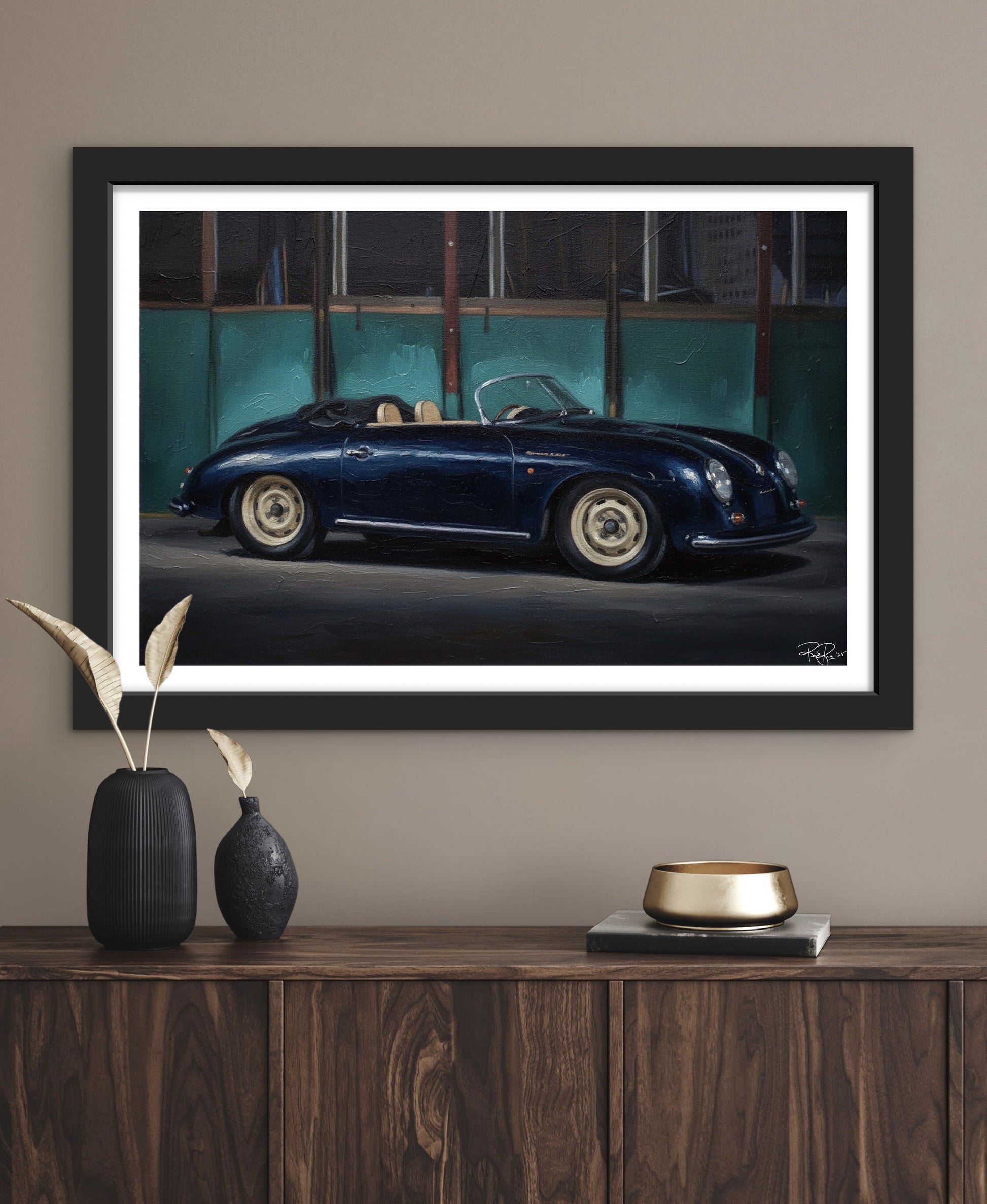 Framed artwork of a vintage car on a wall above a wooden console table.