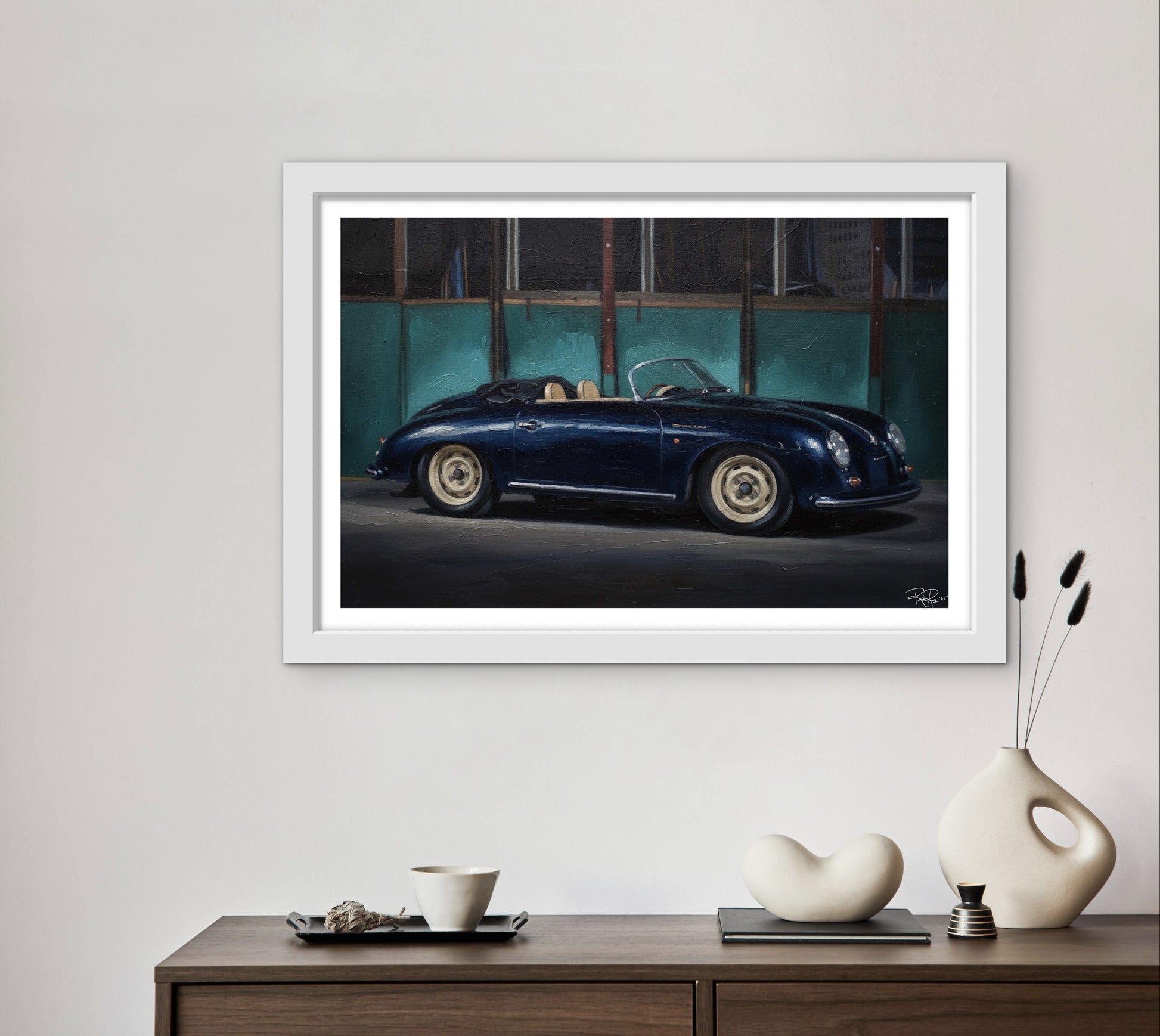 Framed artwork of a classic blue sports car on a wall above a wooden console table with decorative items.