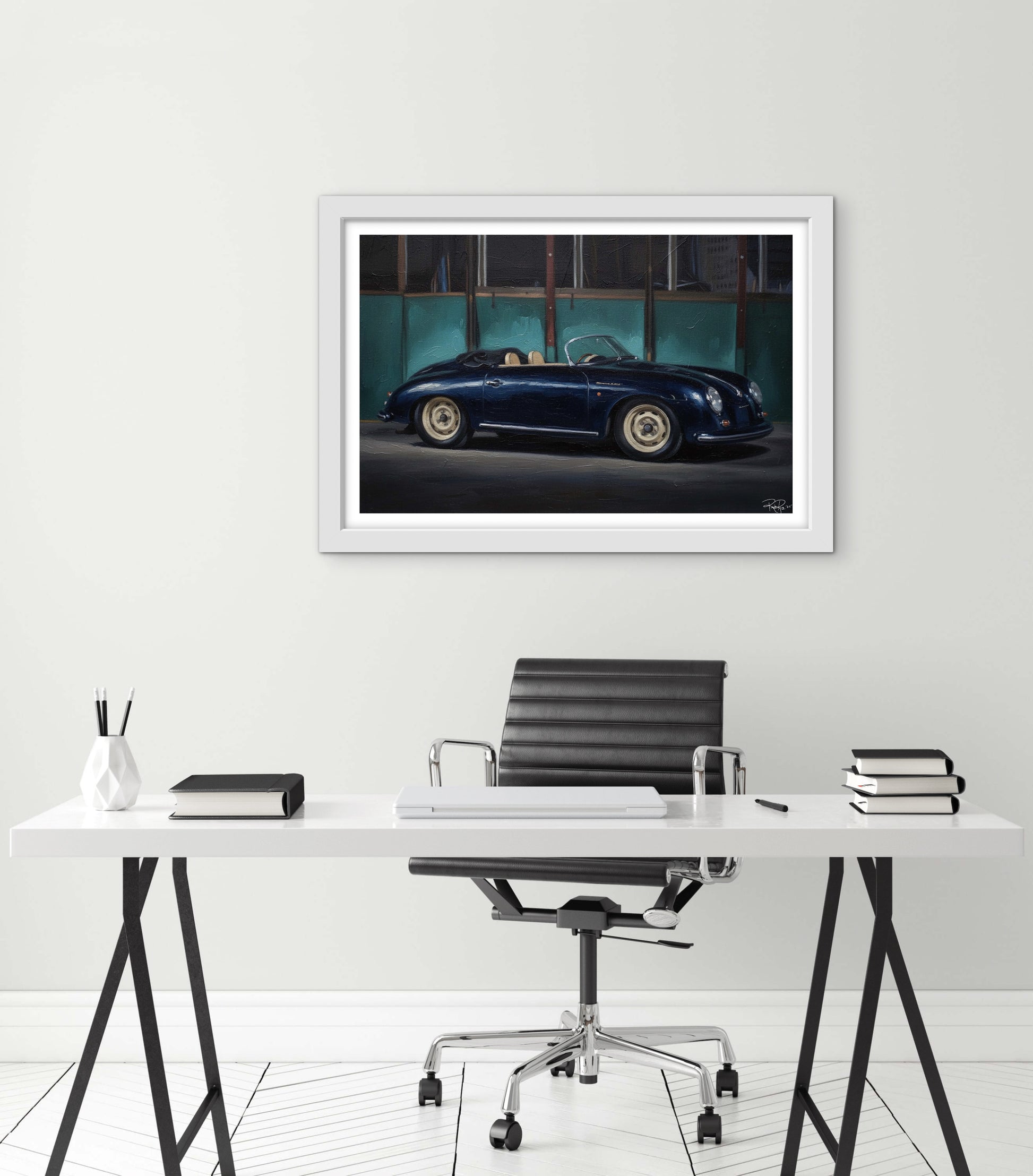 Framed photograph of a vintage car on a wall above a desk.