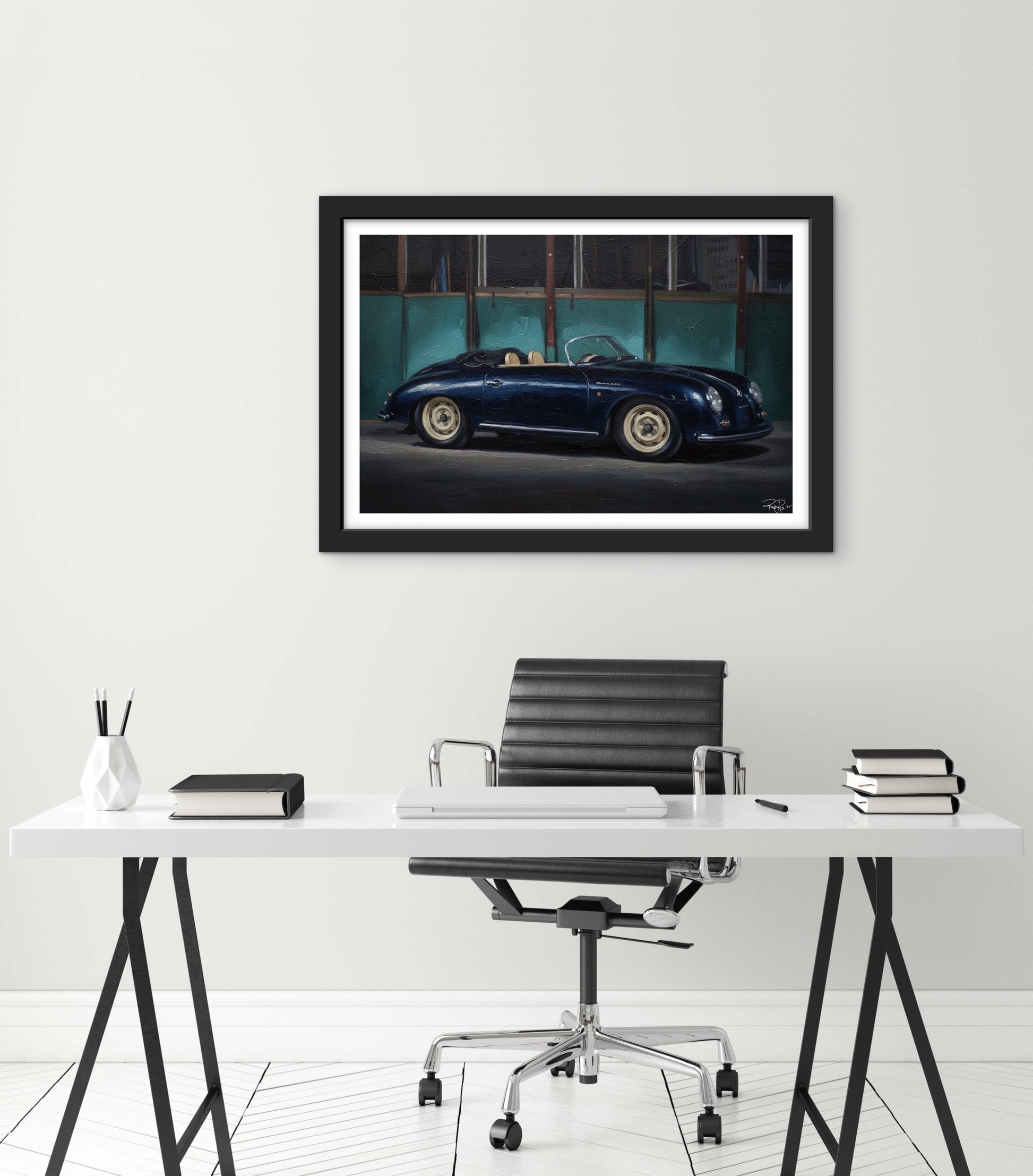 Framed photograph of a classic car on a wall above a desk.
