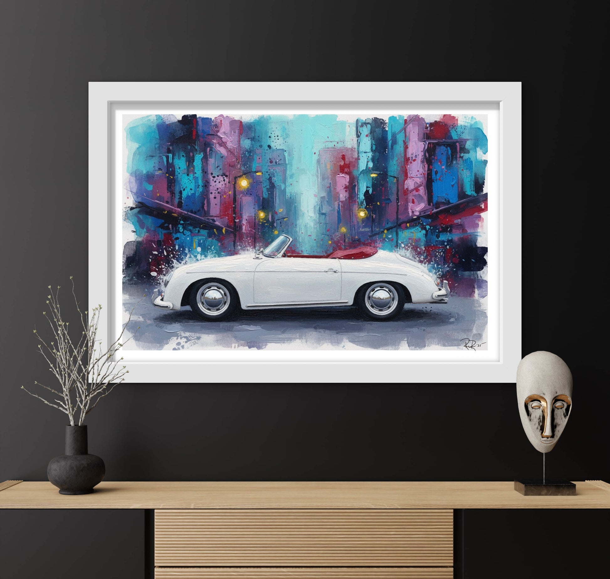 Framed artwork of a white convertible car on a city street with abstract colors, displayed on a dark wall above a wooden shelf.