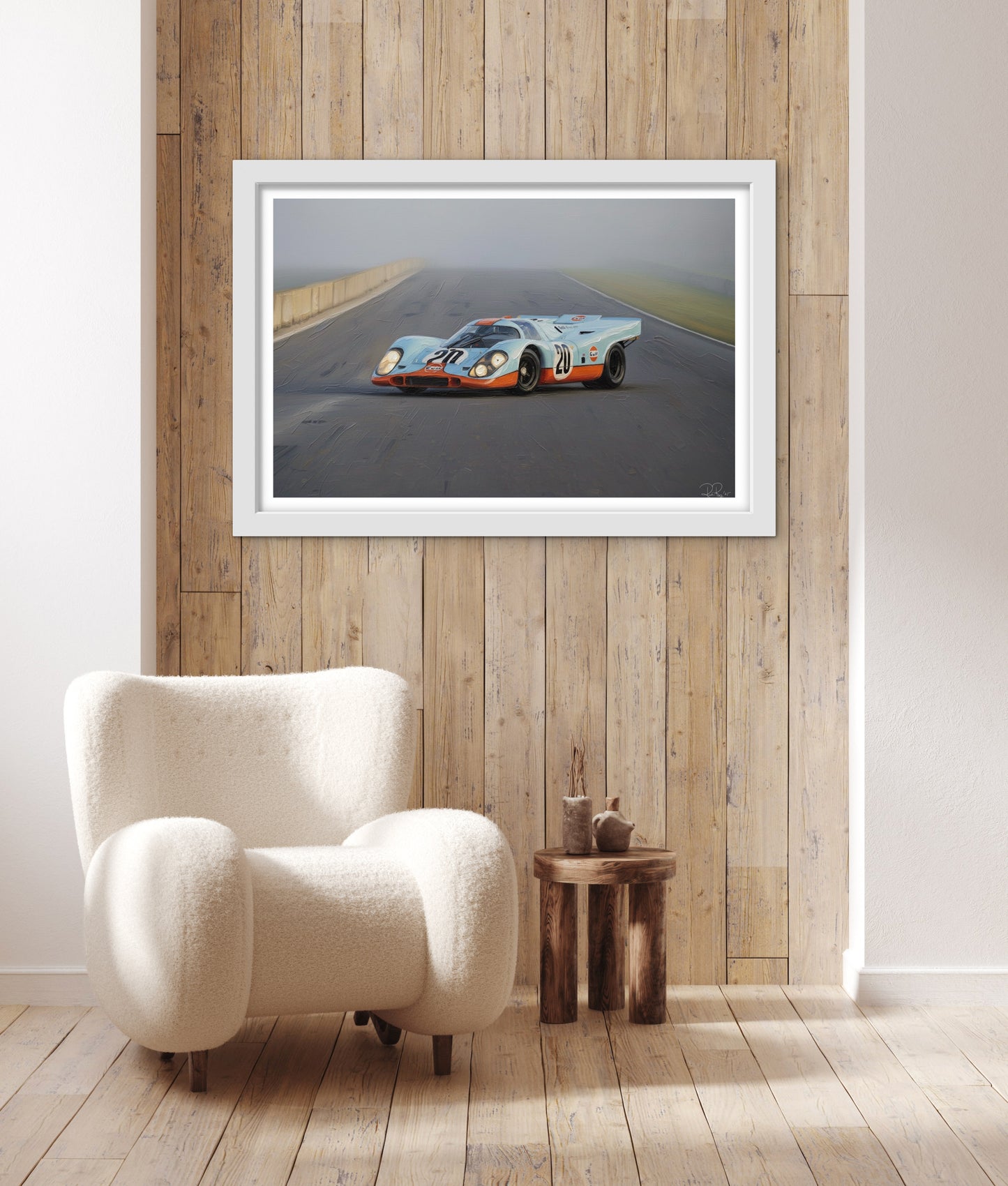 Framed artwork of a race car on a wall above a white armchair.