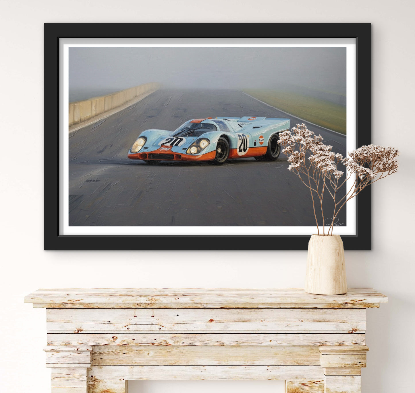 Framed picture of a vintage race car on a road, displayed above a wooden console table.