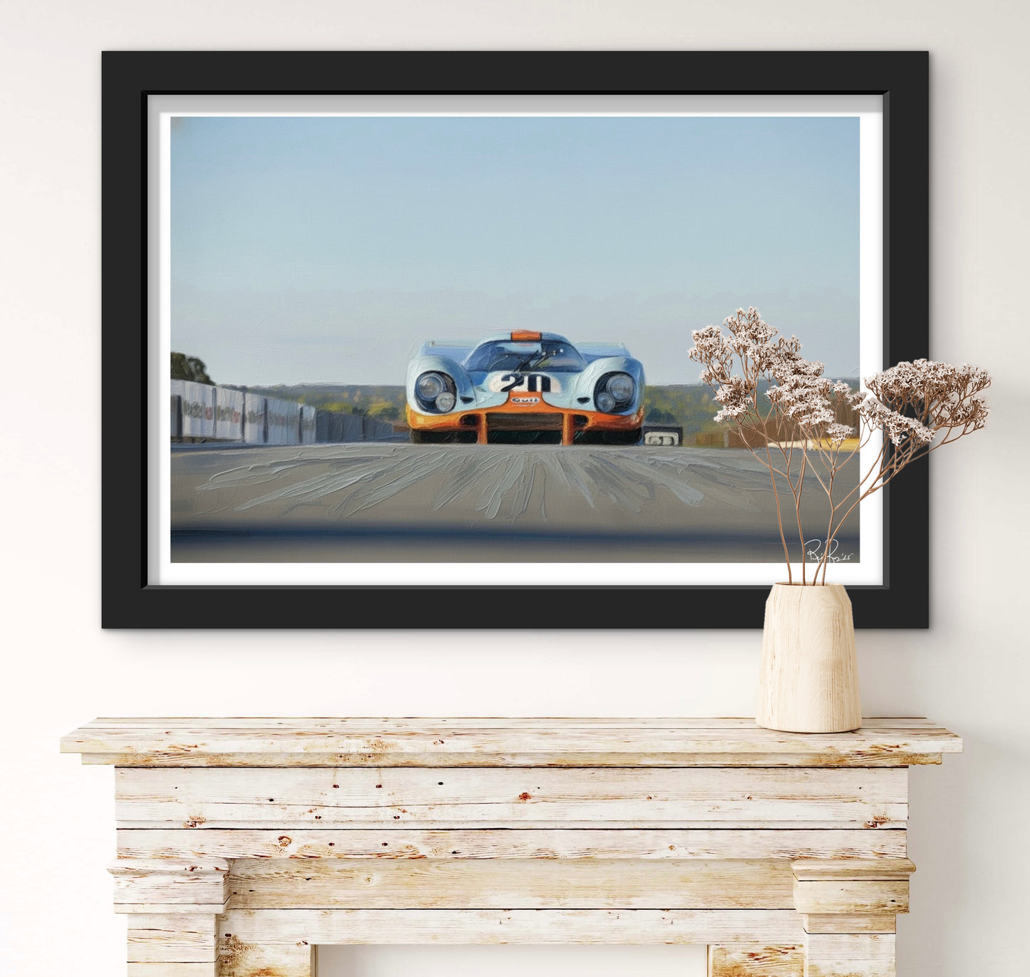 Framed artwork of a vintage race car on a wall above a wooden console table.