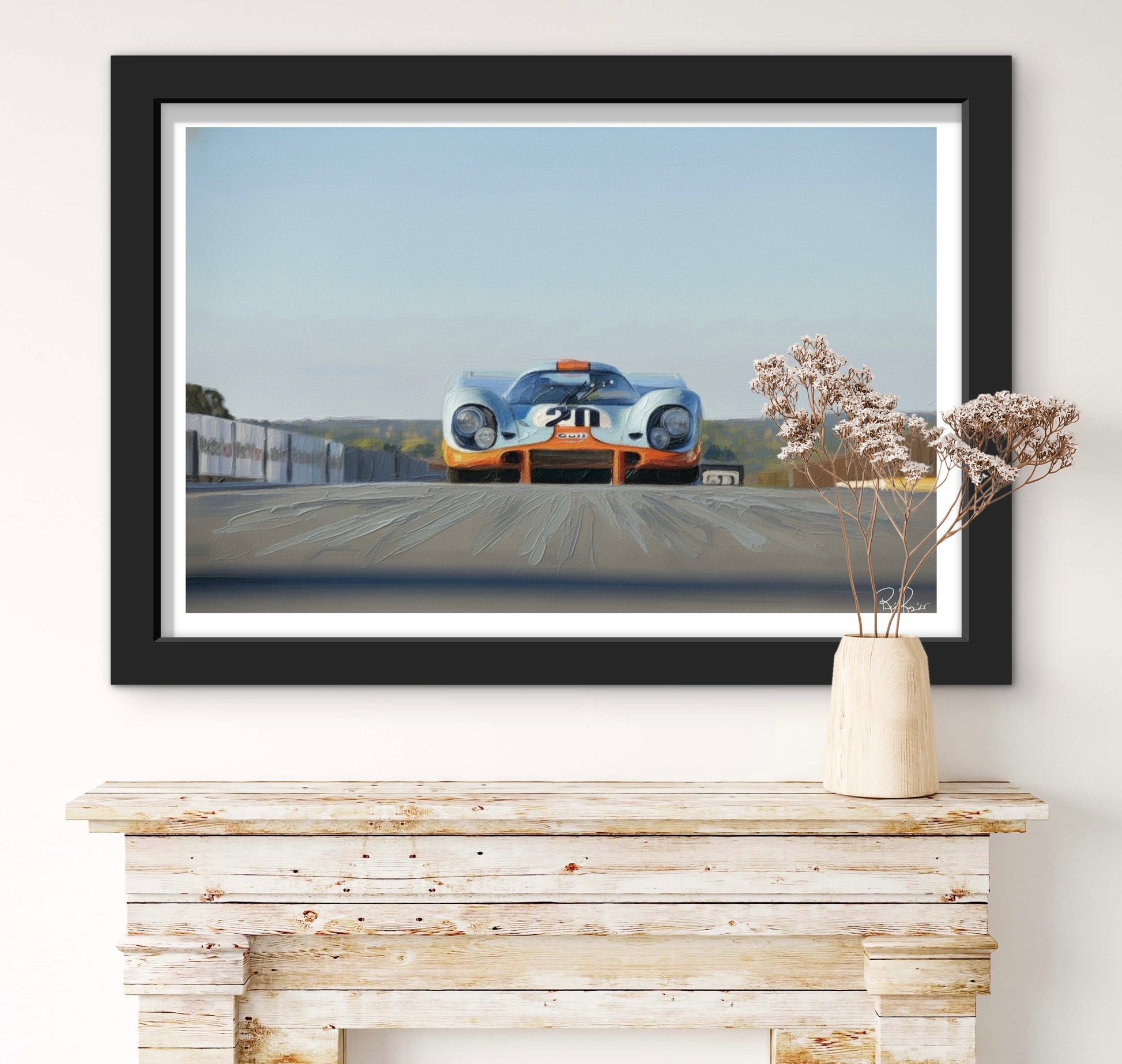 Framed artwork of a vintage race car on a wall above a wooden console table.