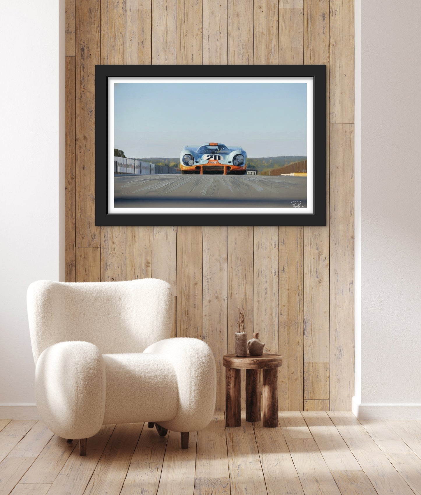 Framed artwork of a race car on a wooden wall above a white armchair.
