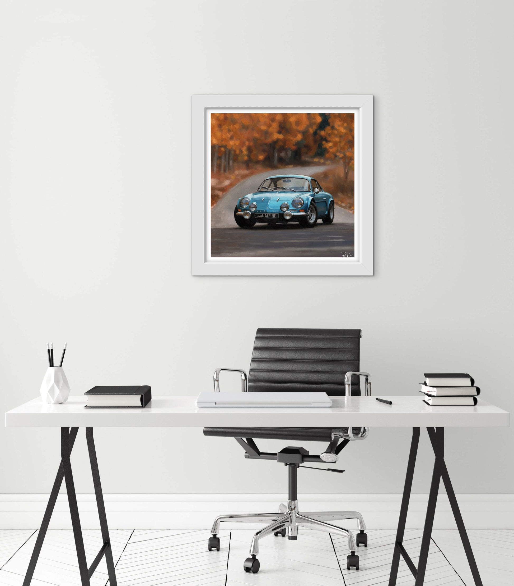 Framed artwork of a blue car on a road with a white desk and chair below it.