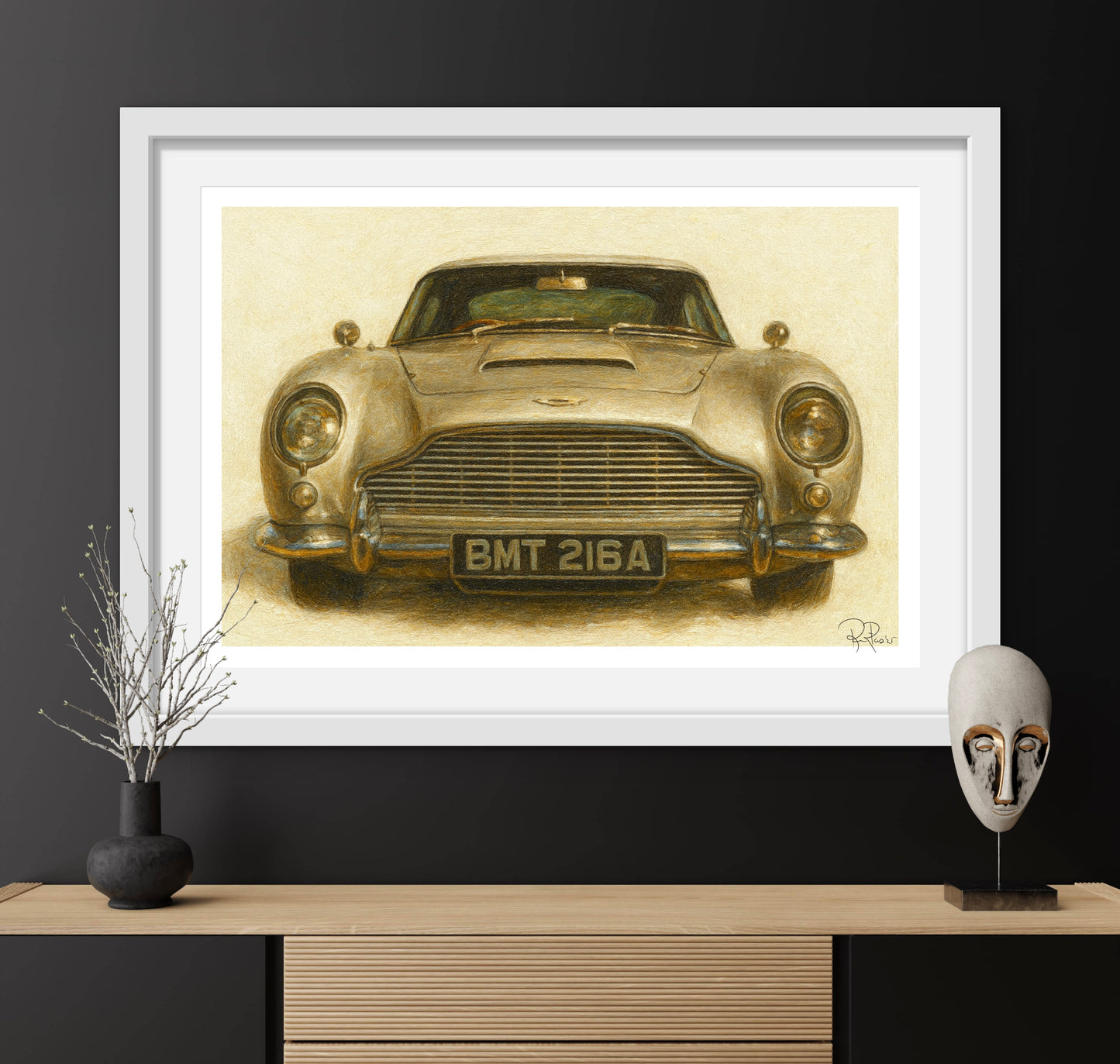 Framed artwork of a vintage car on a dark wall with decorative items below.