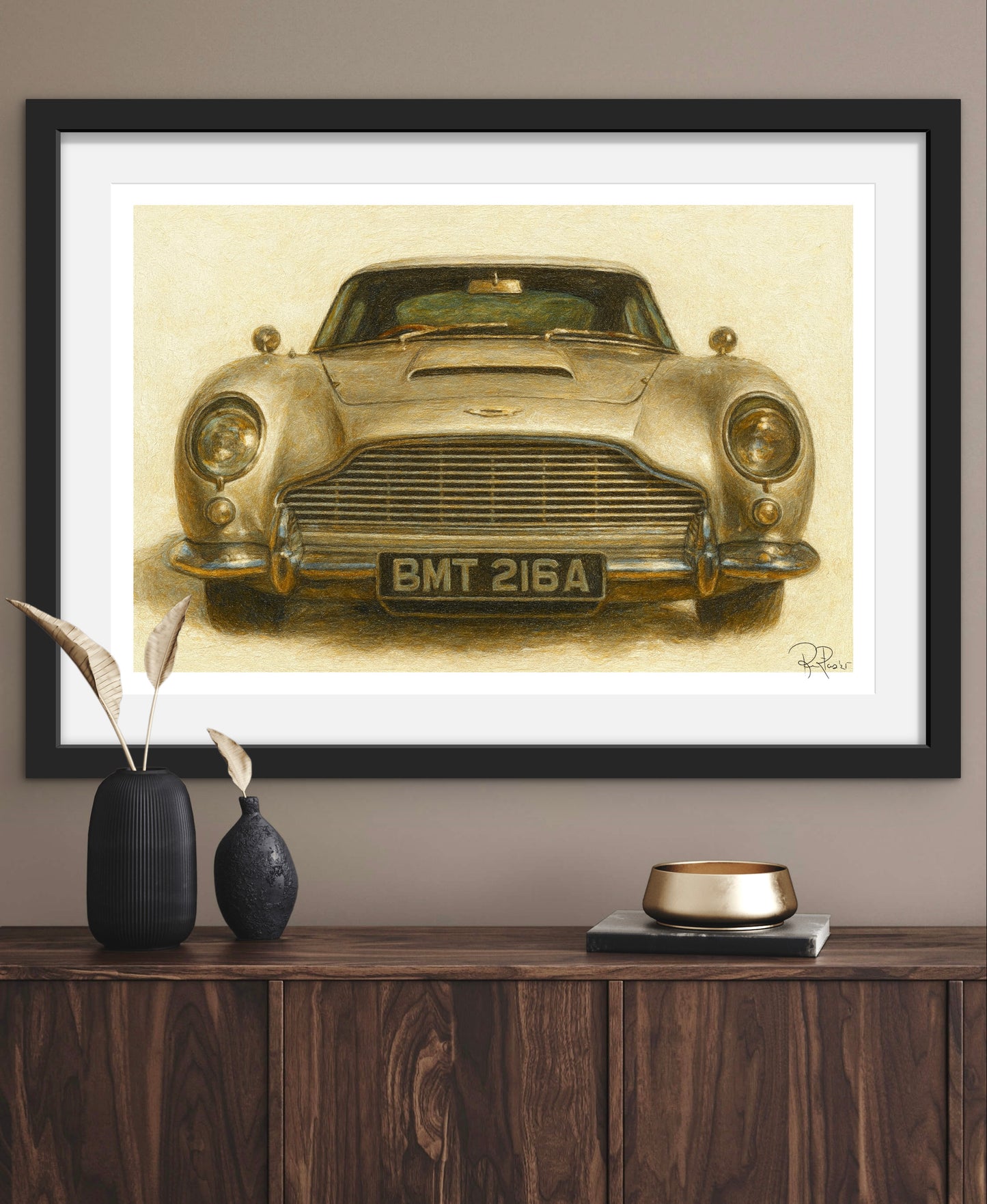 Framed artwork of a vintage car on a wall above a wooden cabinet with decorative items.