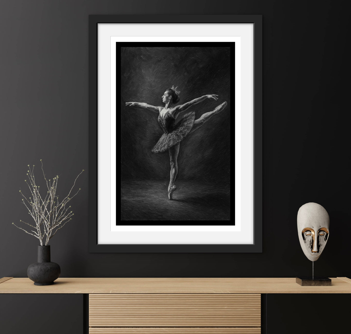 Framed black and white ballet dancer print on a dark wall with decorative items.