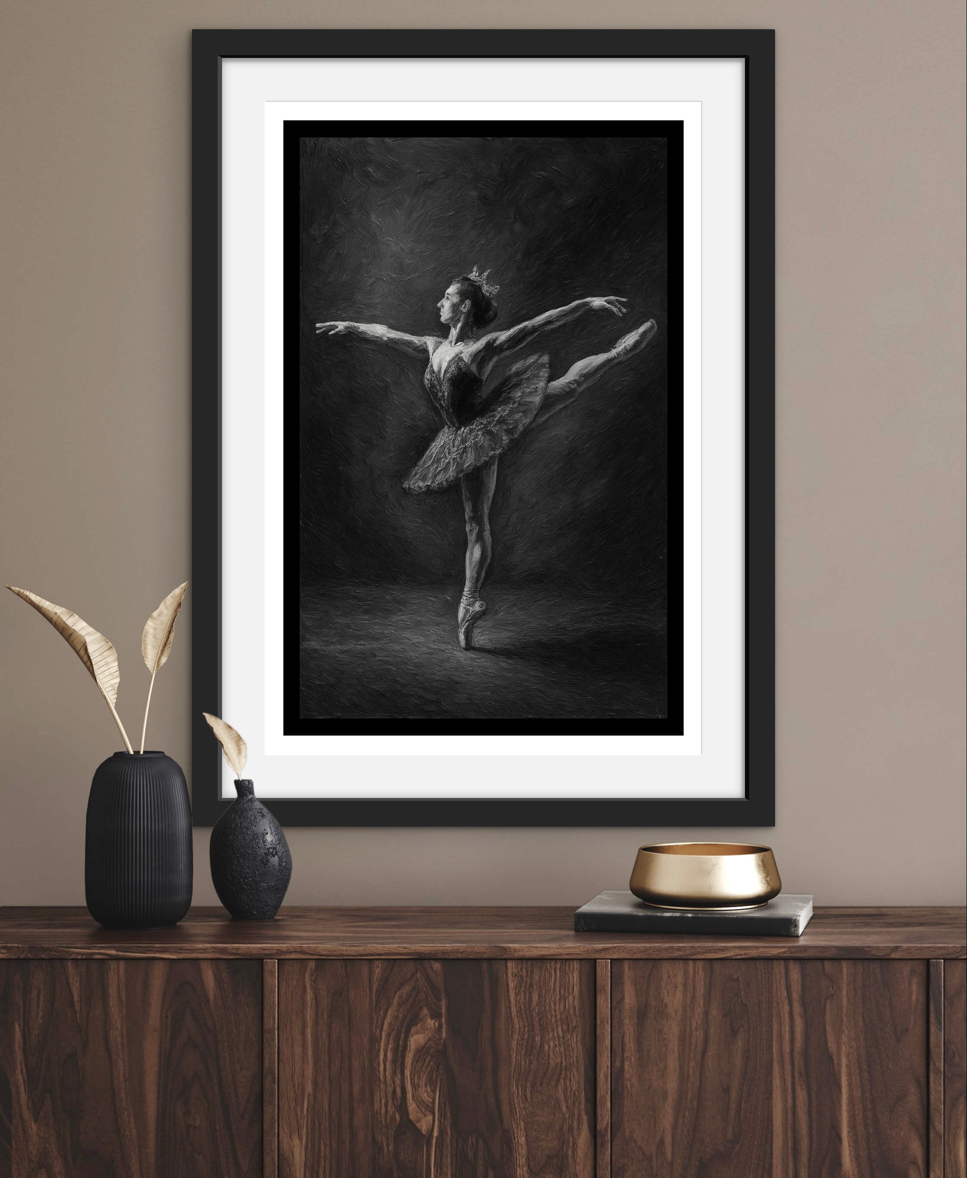 Framed black and white artwork of a dancer on a wooden console table with decorative items.