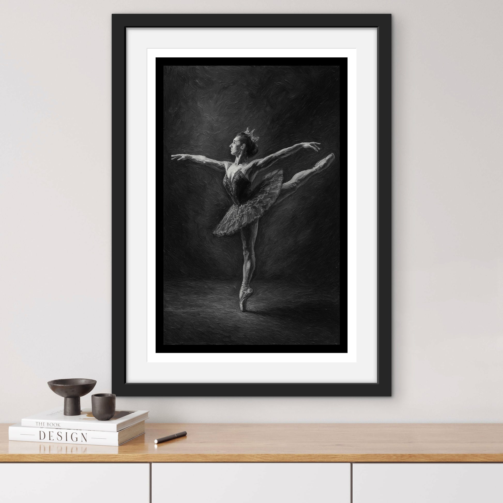 Framed black and white artwork of a ballerina on a wall above a wooden shelf.