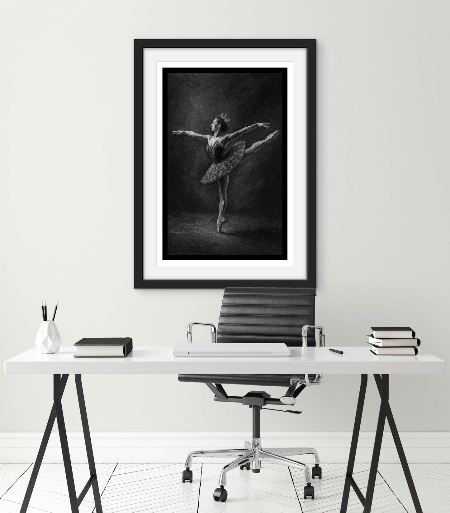 Framed black and white artwork of a dancer on a desk with office chair