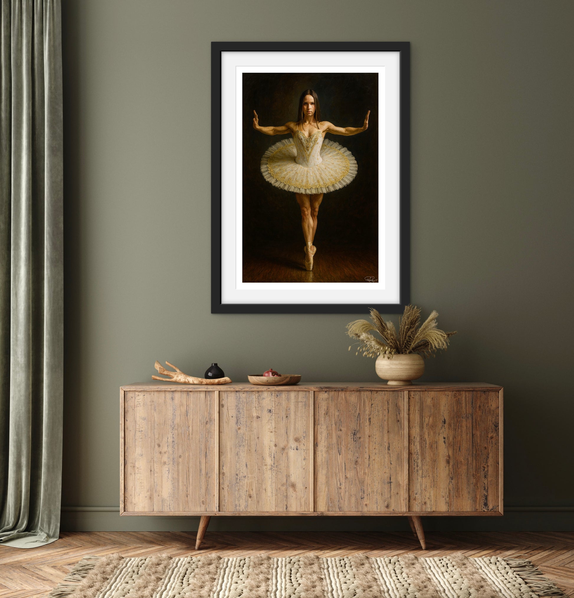 Framed artwork of a ballerina on a wall above a wooden cabinet.