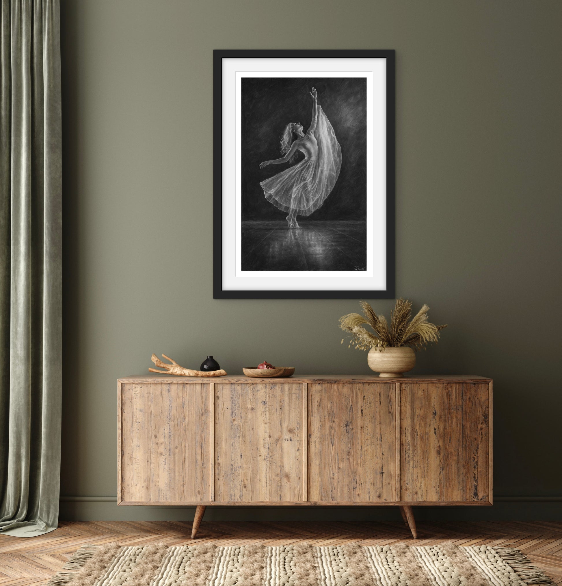 Framed artwork of a dancer in a dark room above a wooden sideboard.