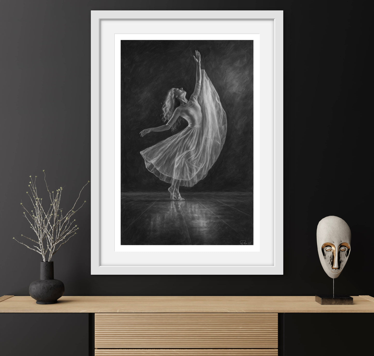 Framed black and white artwork of a dancer on a dark wall with decorative items below.