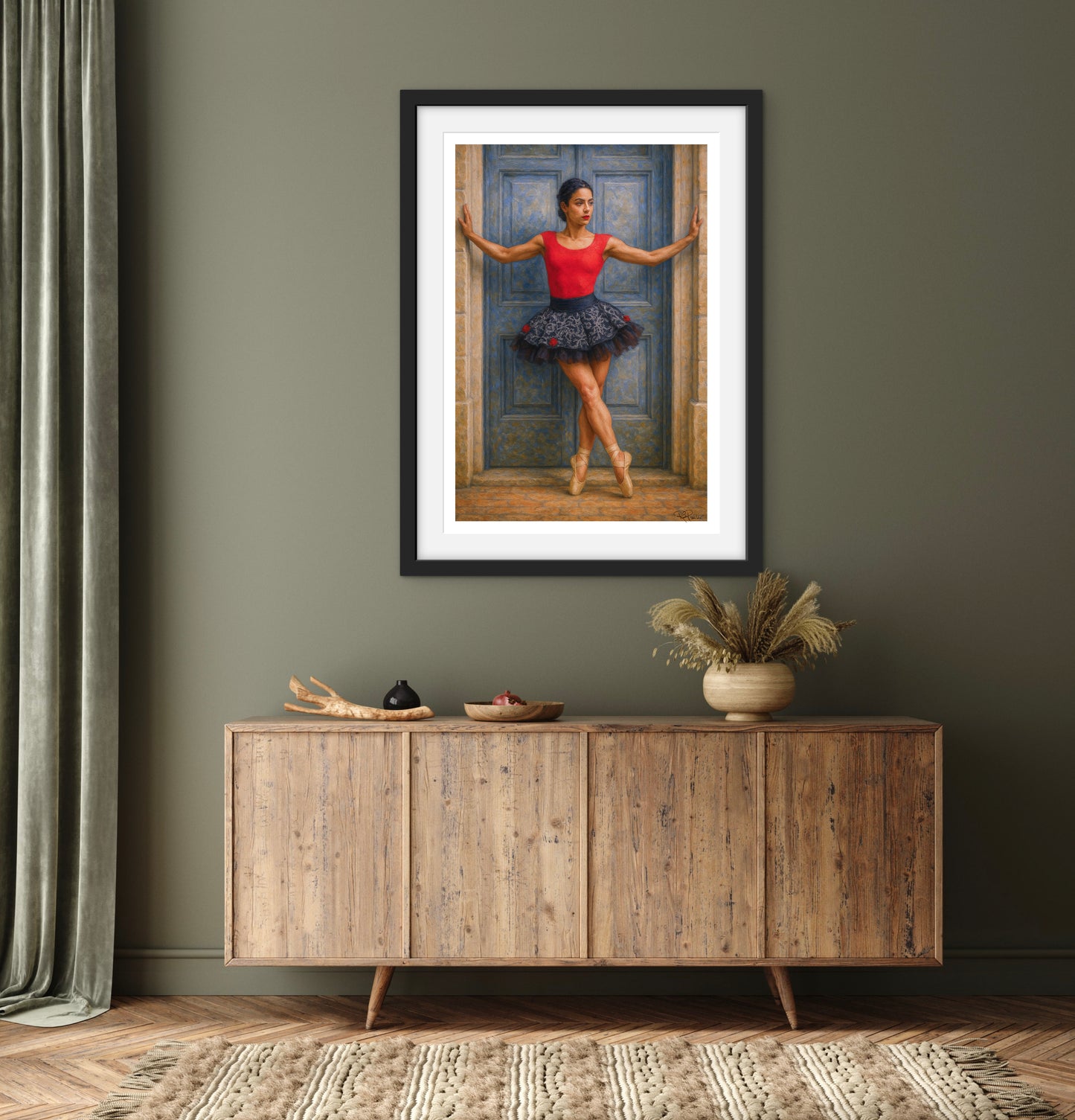 Framed artwork of a dancer in a red top and blue skirt on a gray wall above a wooden sideboard.
