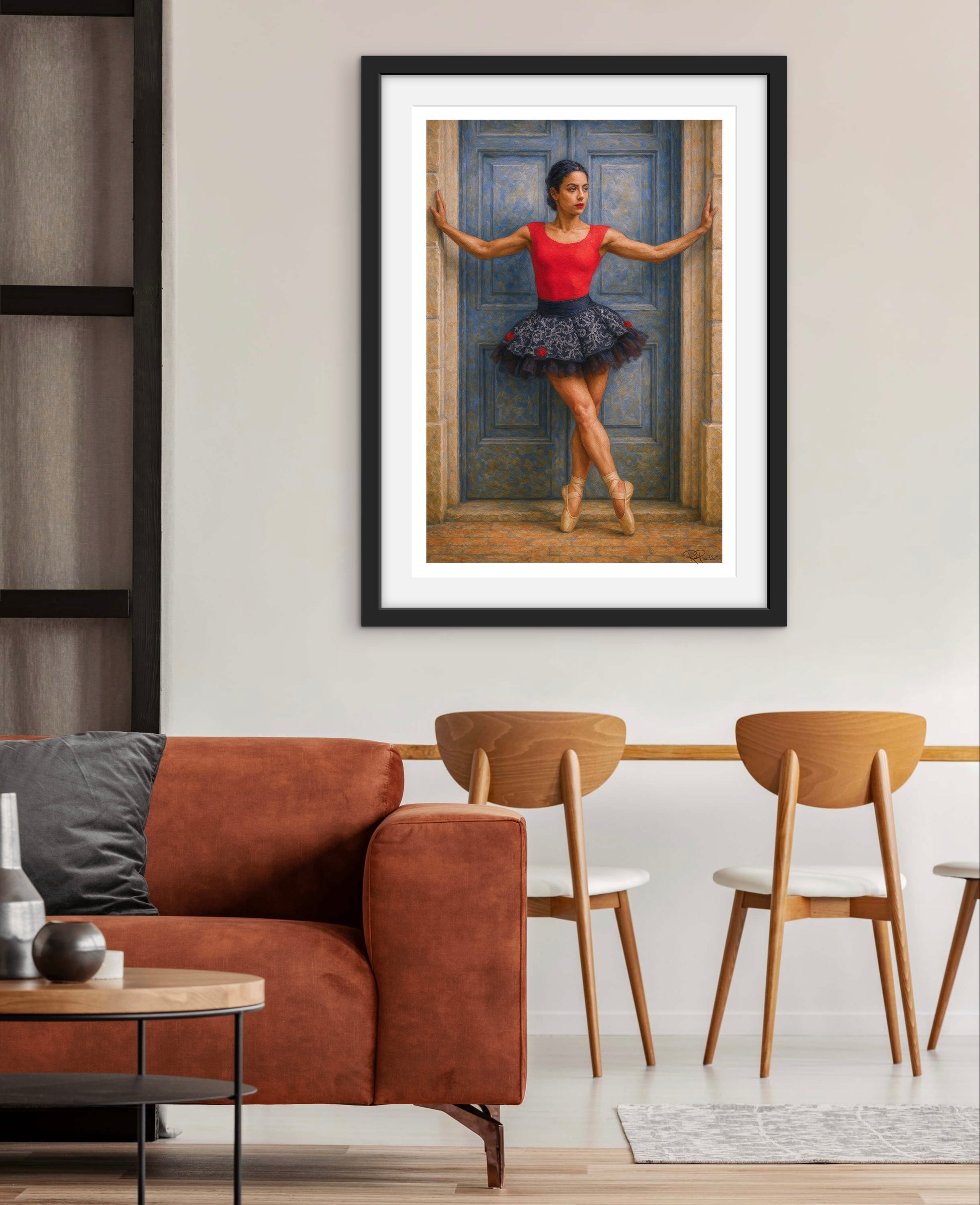 Framed artwork of a ballerina in a living room setting with a brown sofa and wooden chairs.
