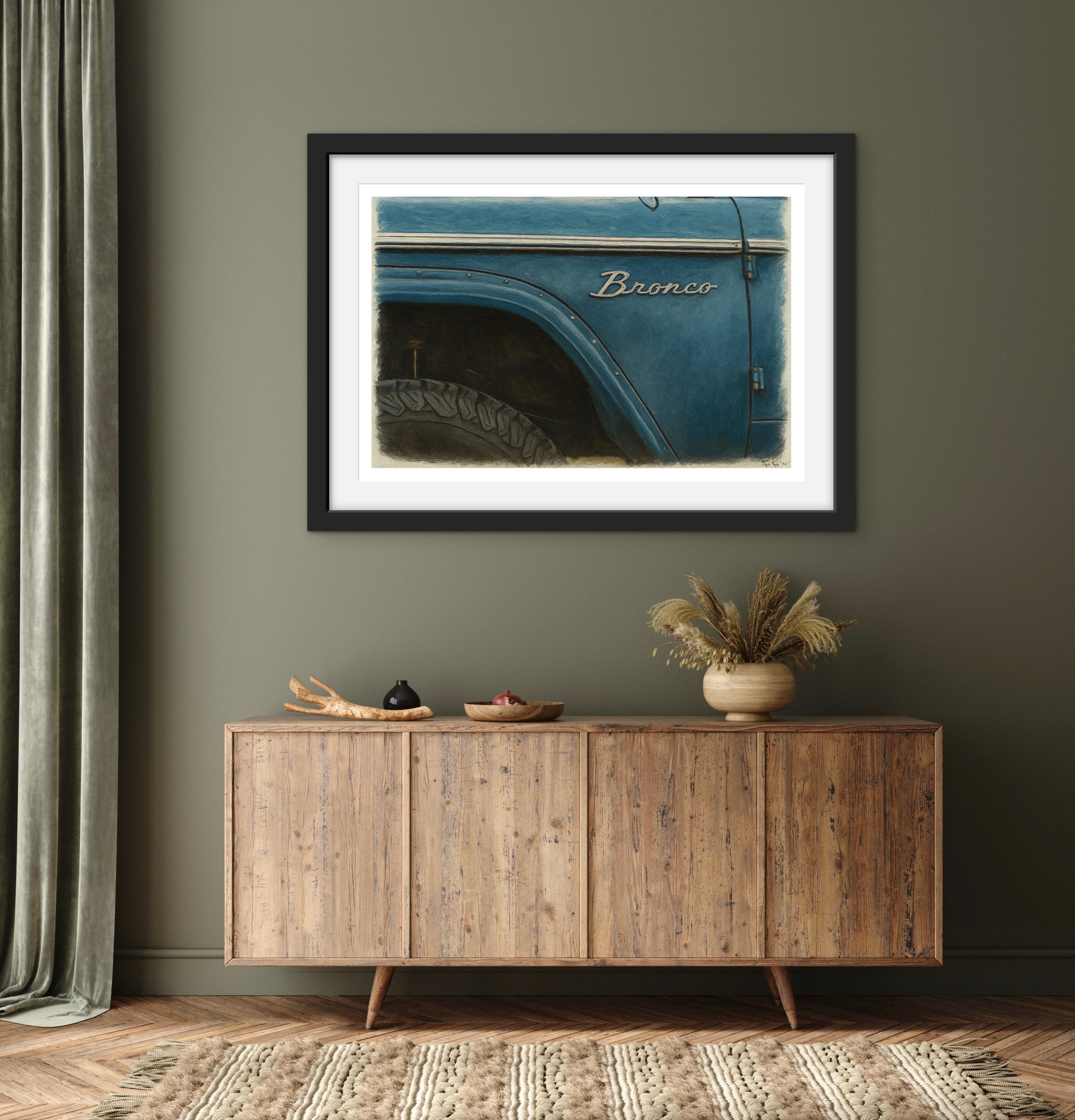 Framed picture of a blue Bronco on a wall above a wooden sideboard.