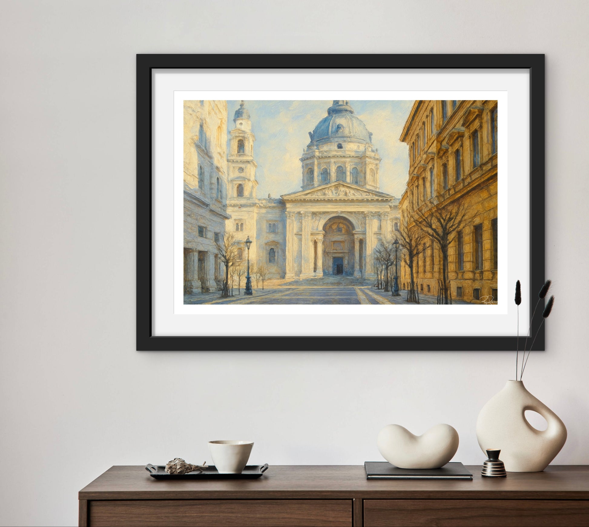 Framed artwork of a cityscape with a large building on a wall above a wooden console table.