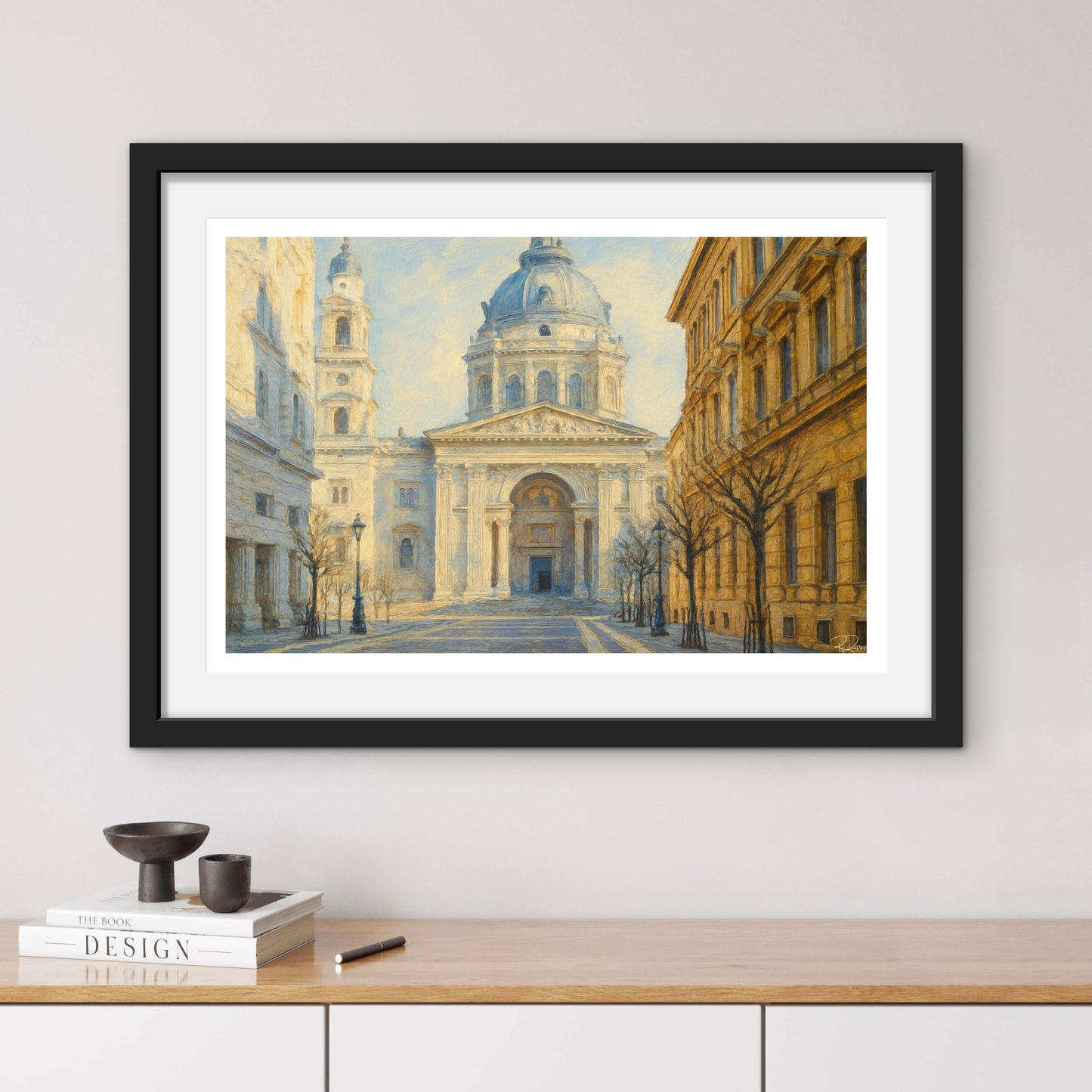 Framed artwork of a classical building on a wall above a wooden shelf.