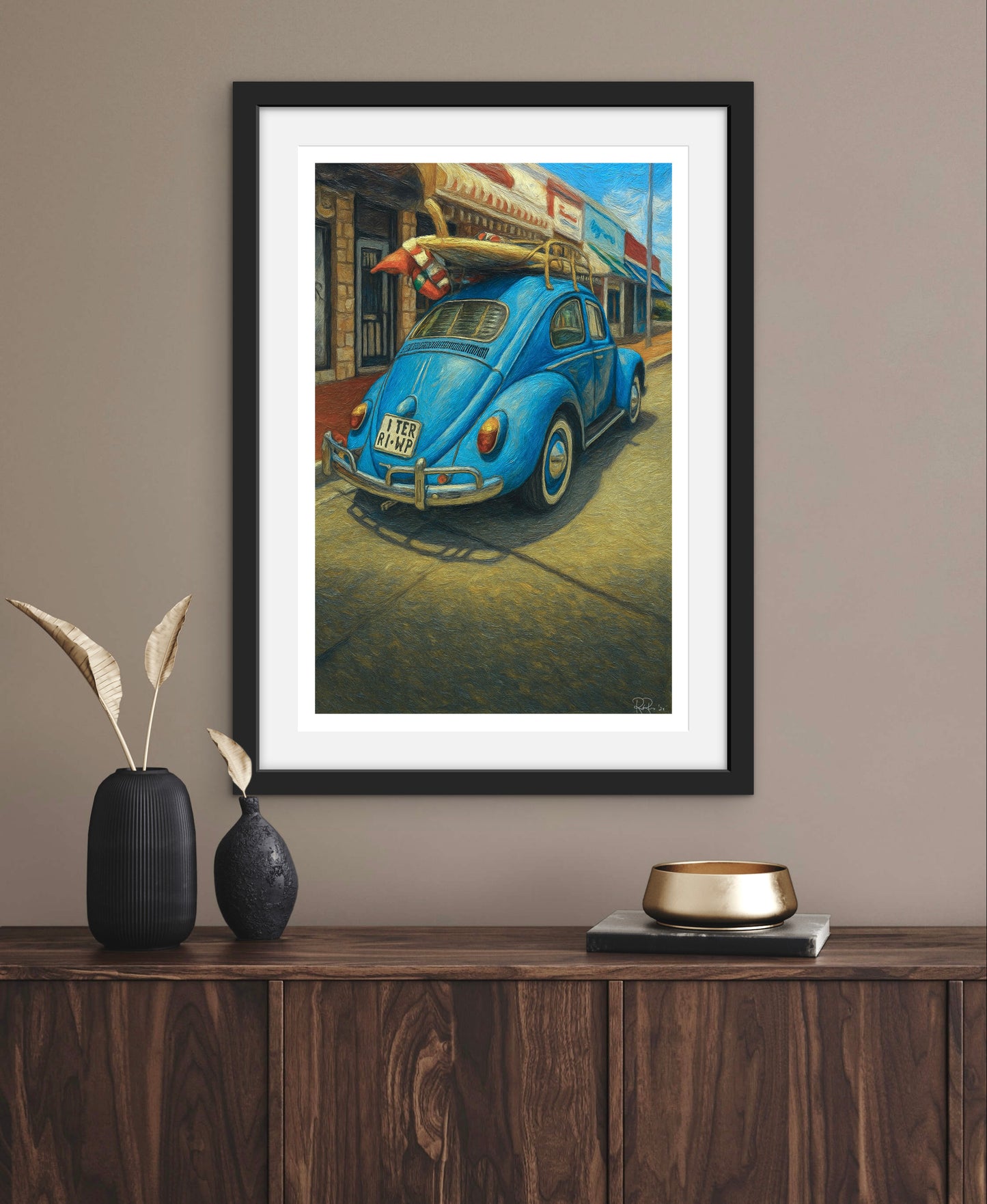 Framed artwork of a blue vintage car on a wall above a wooden console table.