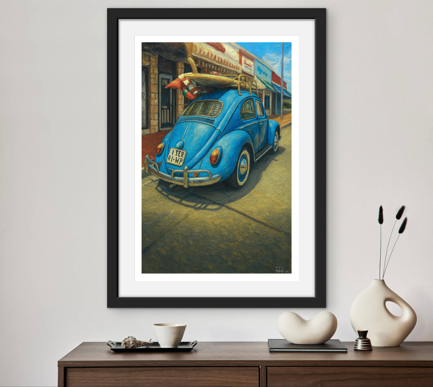 Framed painting of a blue vintage car on a wall above a wooden console table with decorative items.