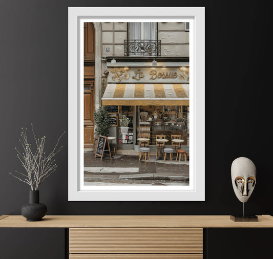 Framed photograph of a street scene with a cafe on a black wall.