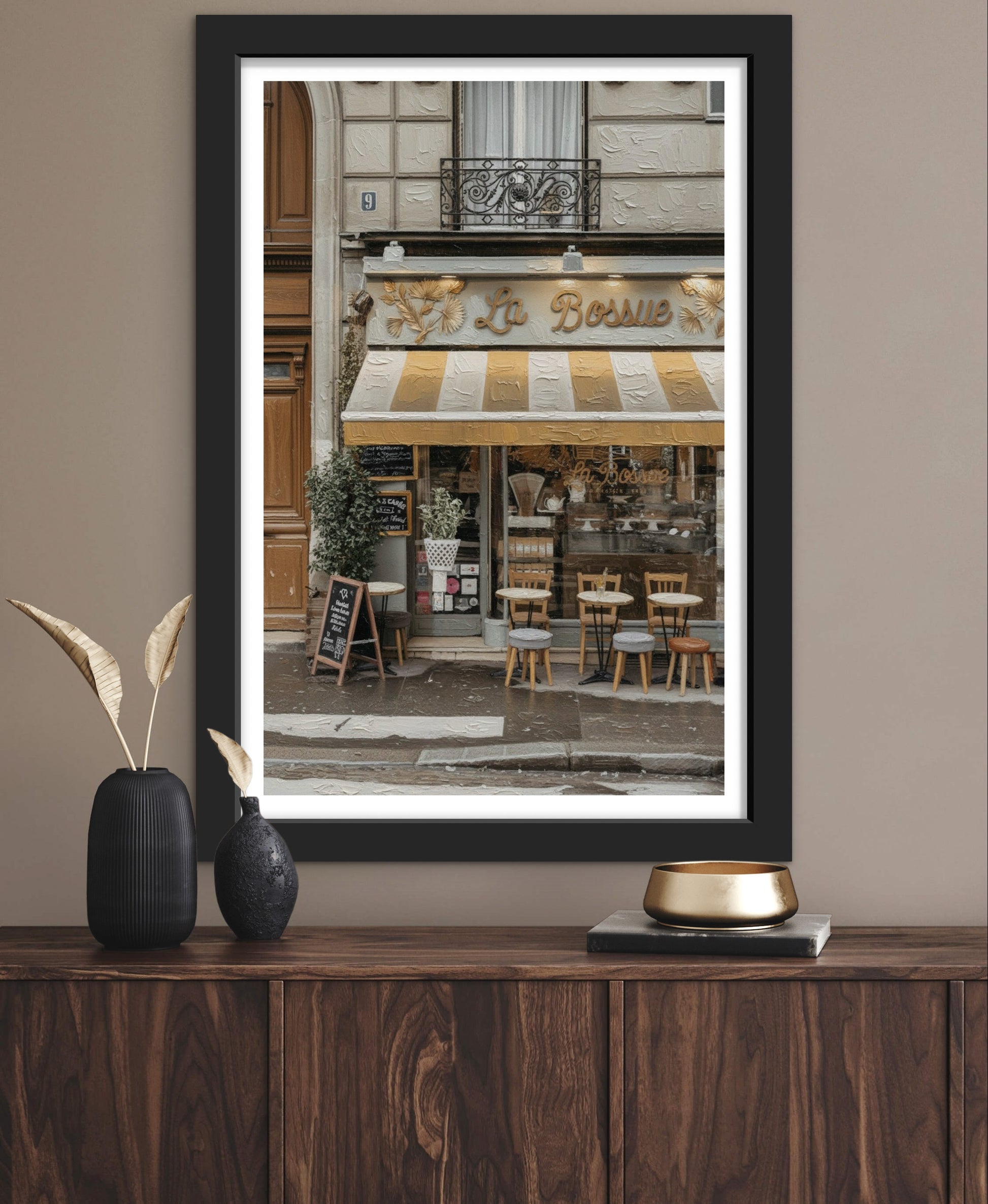 Framed photograph of a café exterior on a wooden surface with decorative items.