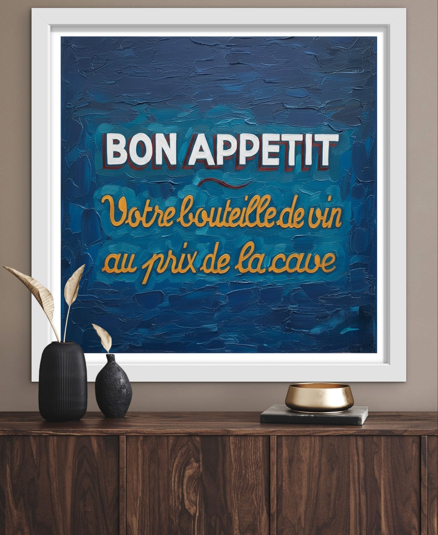 Framed artwork with 'Bon Appetit' text on a blue background, displayed on a wooden surface.