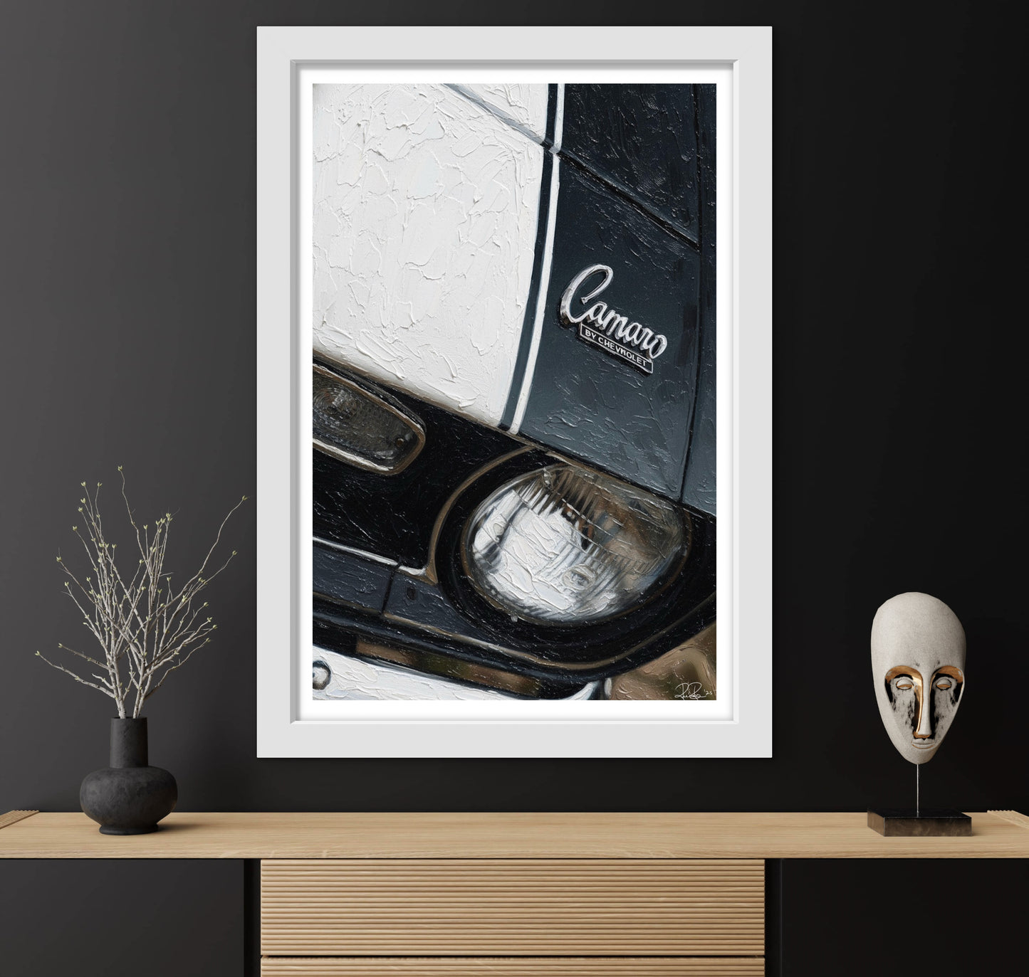 Framed artwork of a car's headlight with 'Camaro' logo on a dark wall.