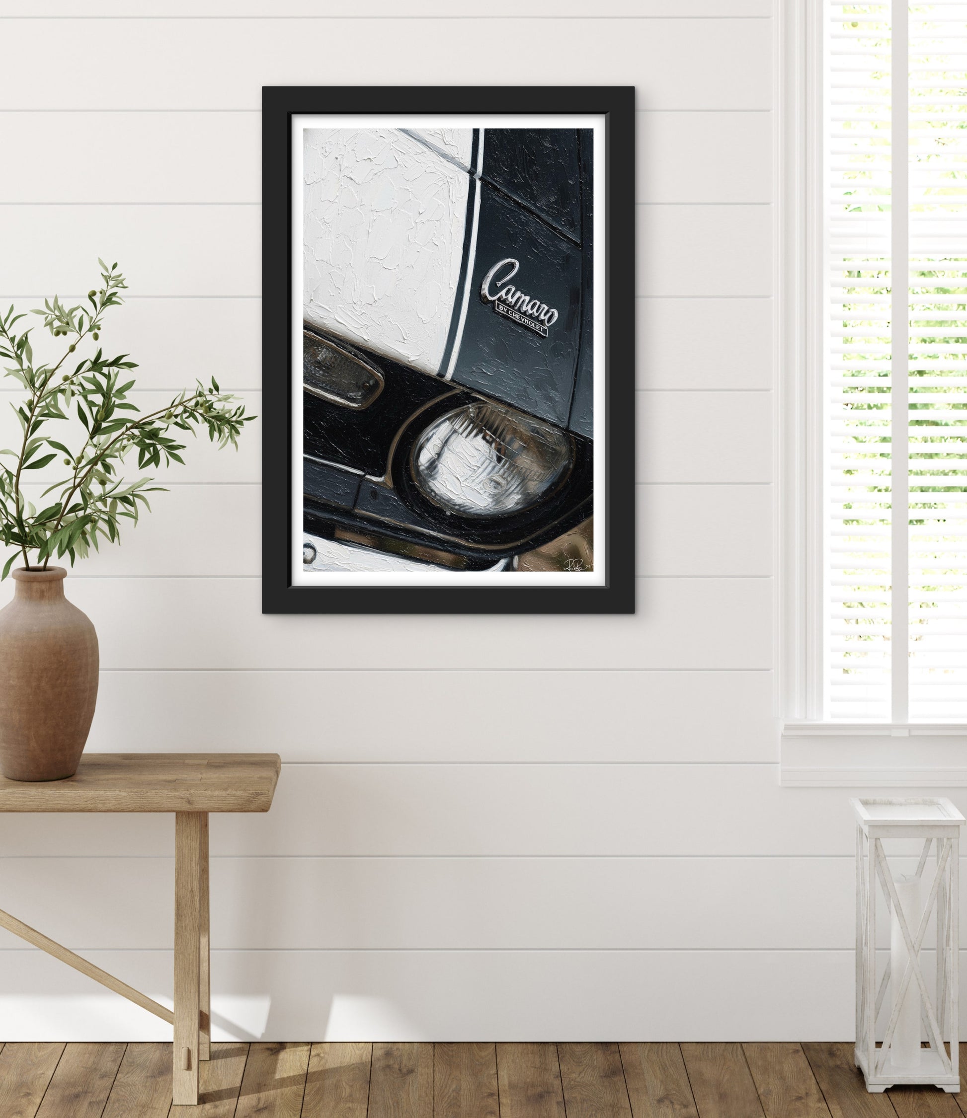 Framed picture of a car interior with 'Camaro' branding on a white wall.