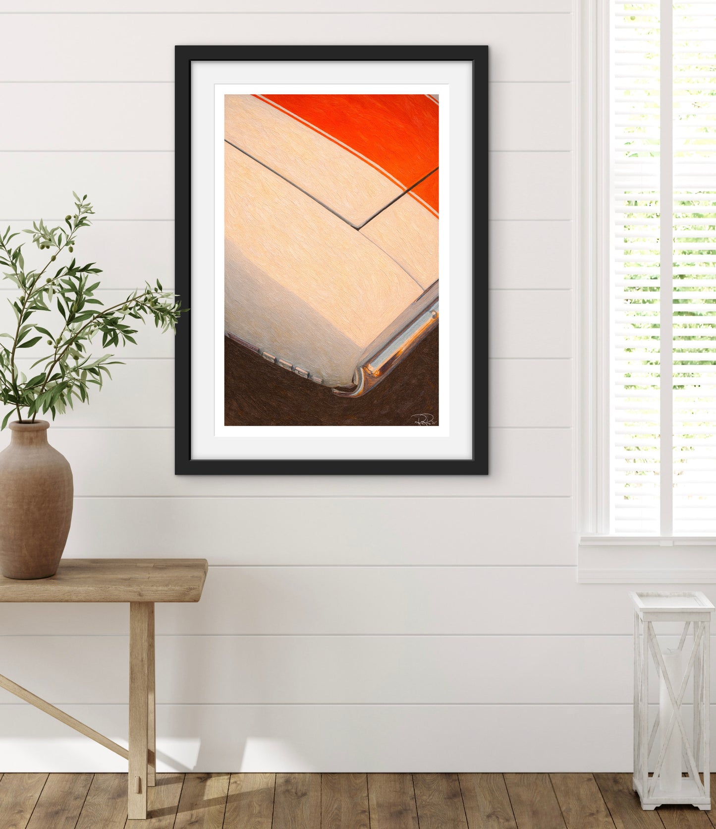 Framed abstract art piece on a white wall with a wooden bench and plant.