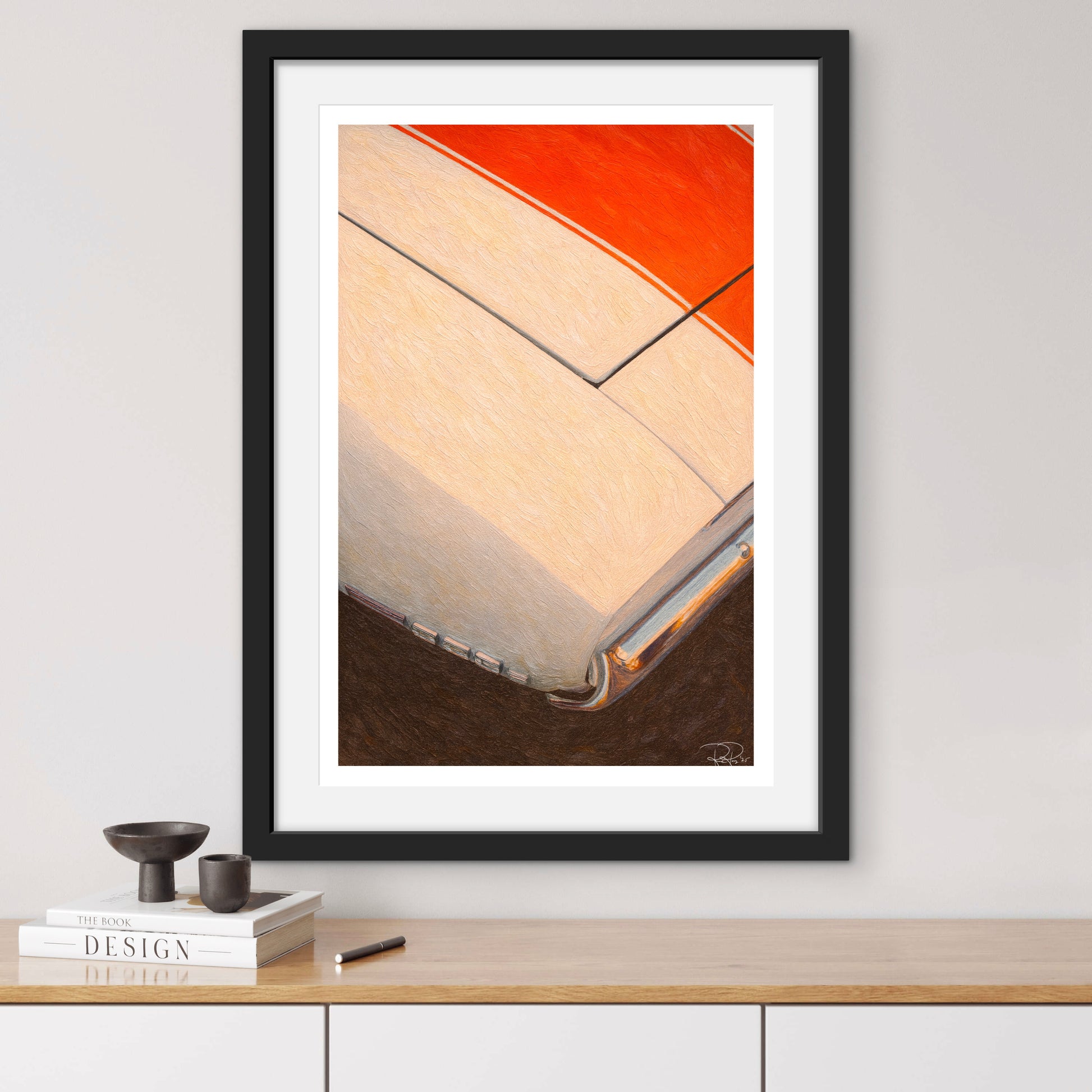 Framed abstract art piece on a wall above a wooden shelf with books and decor items.