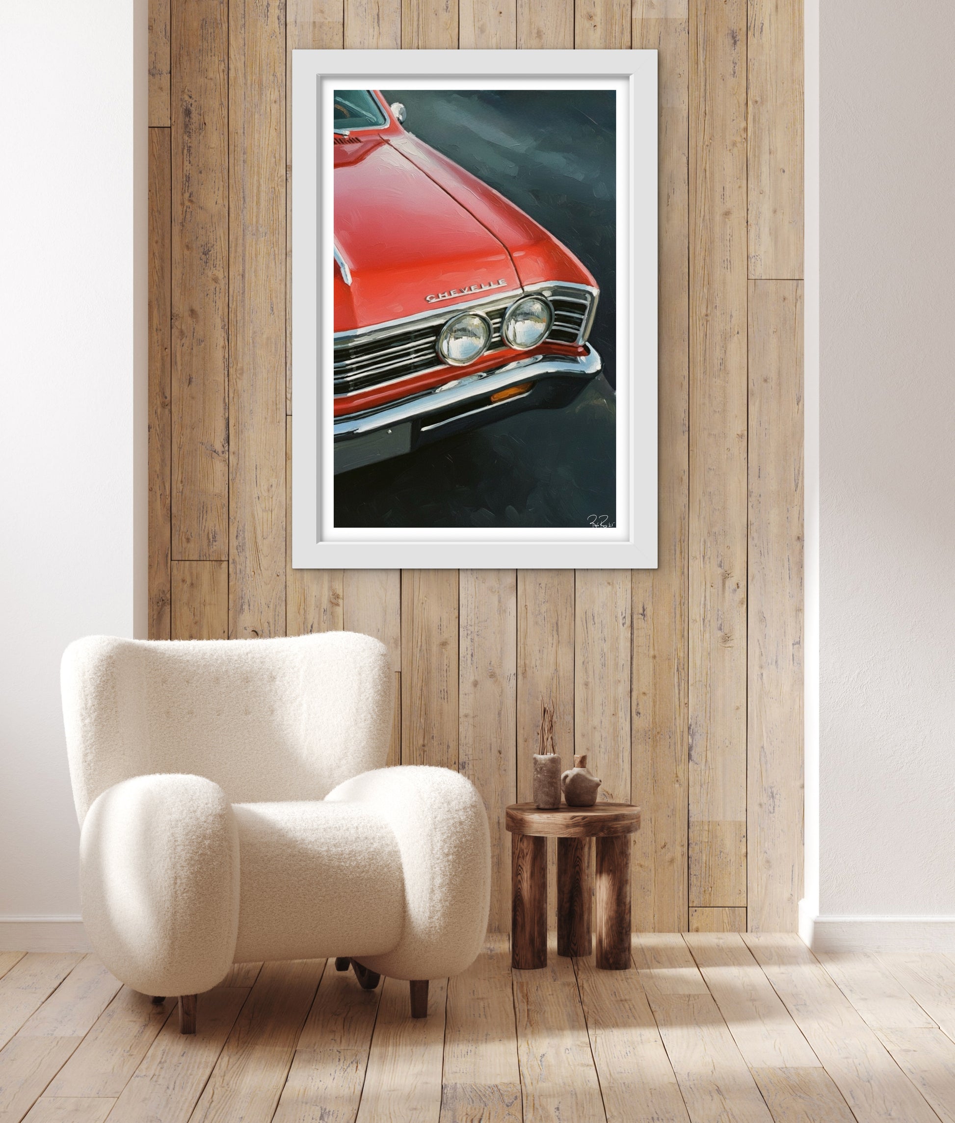 Framed picture of a red car on a wooden wall above a white armchair.