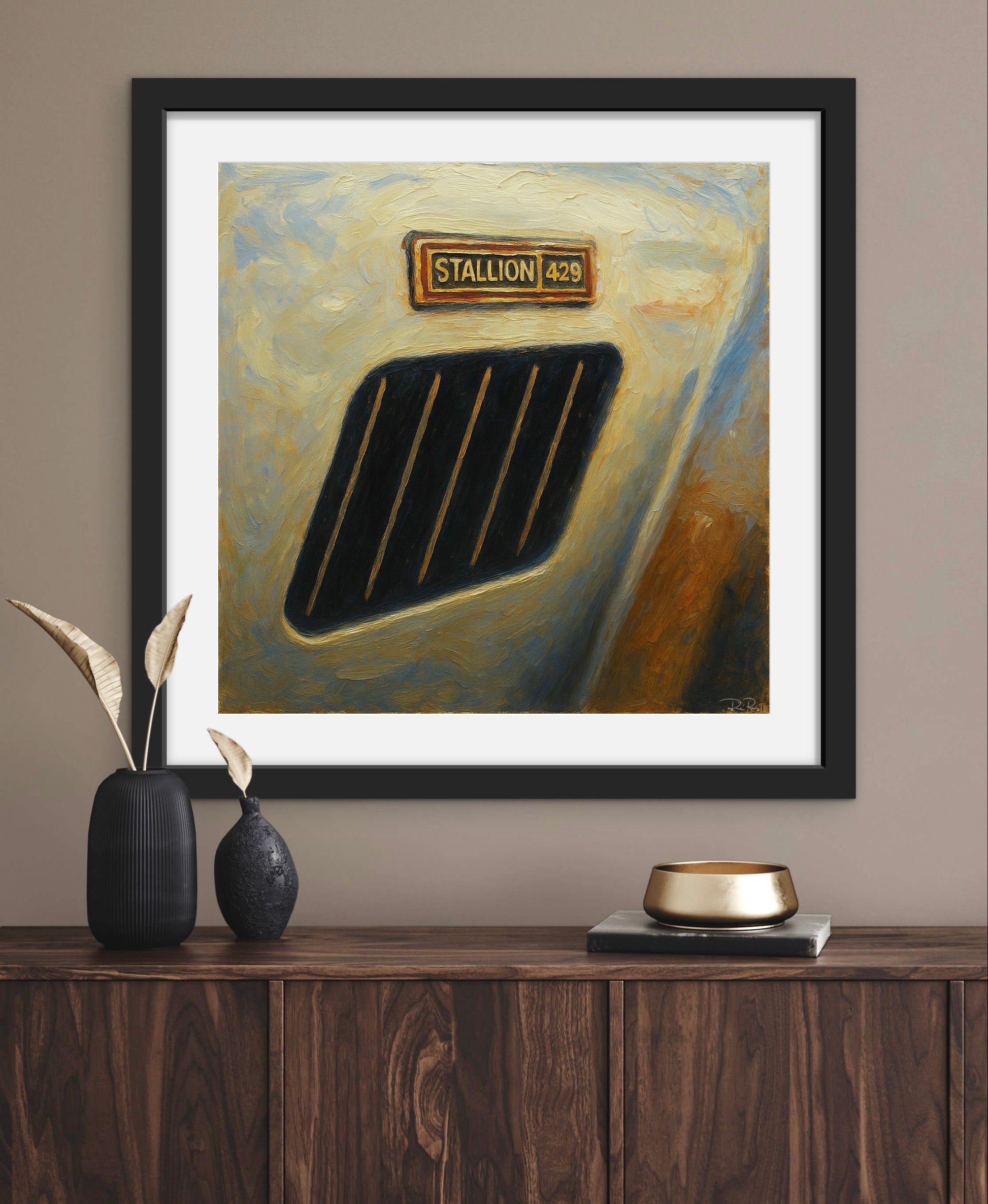 Framed painting of a car grille with 'Stallion' logo on a wall above a wooden cabinet.