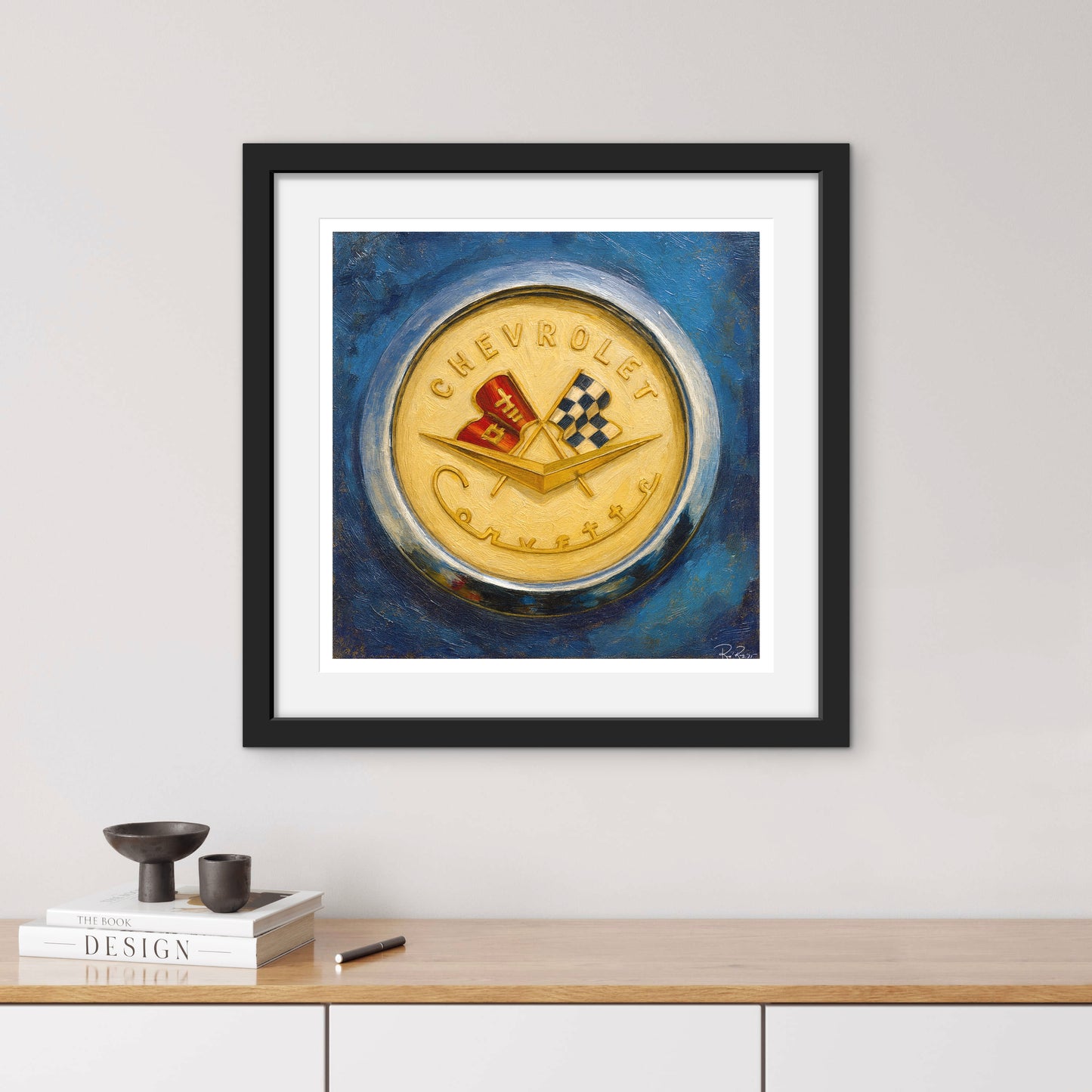 Framed artwork of a Chevrolet logo on a blue background, displayed on a wall above a wooden shelf.