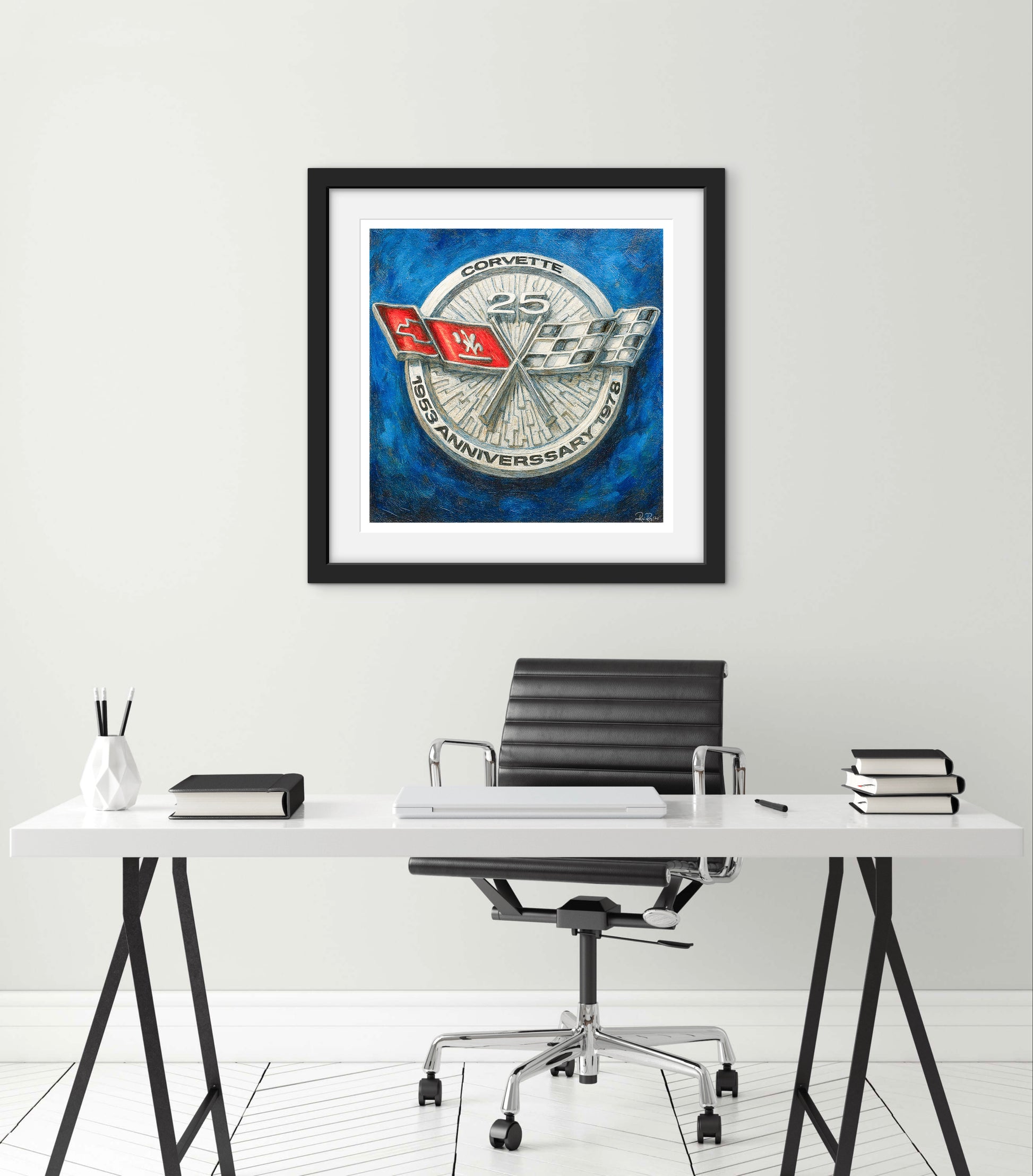 Framed artwork of a Corvette logo on a wall above a desk.