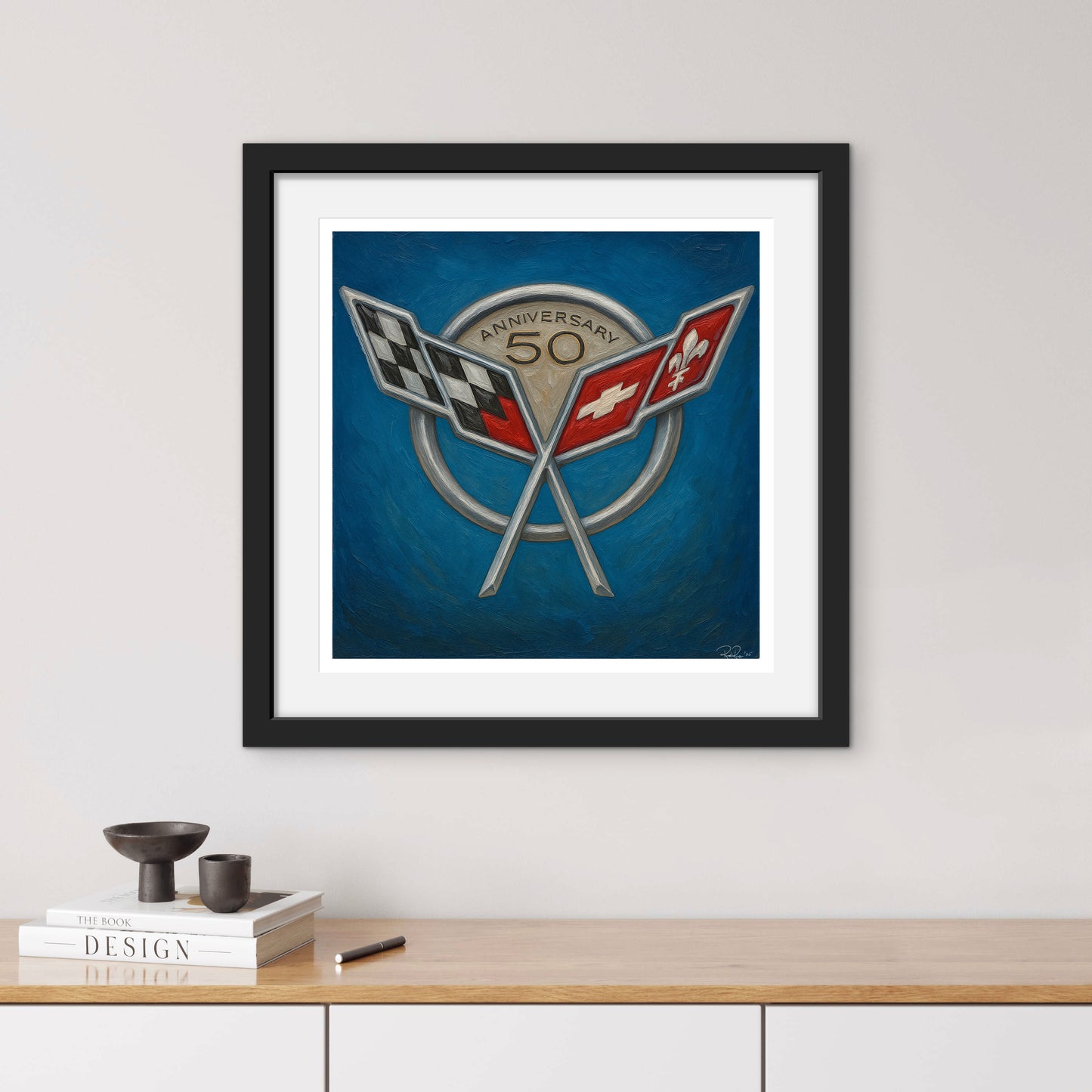 Framed artwork with a design of two crossed flags on a blue background, displayed on a wall above a wooden shelf.