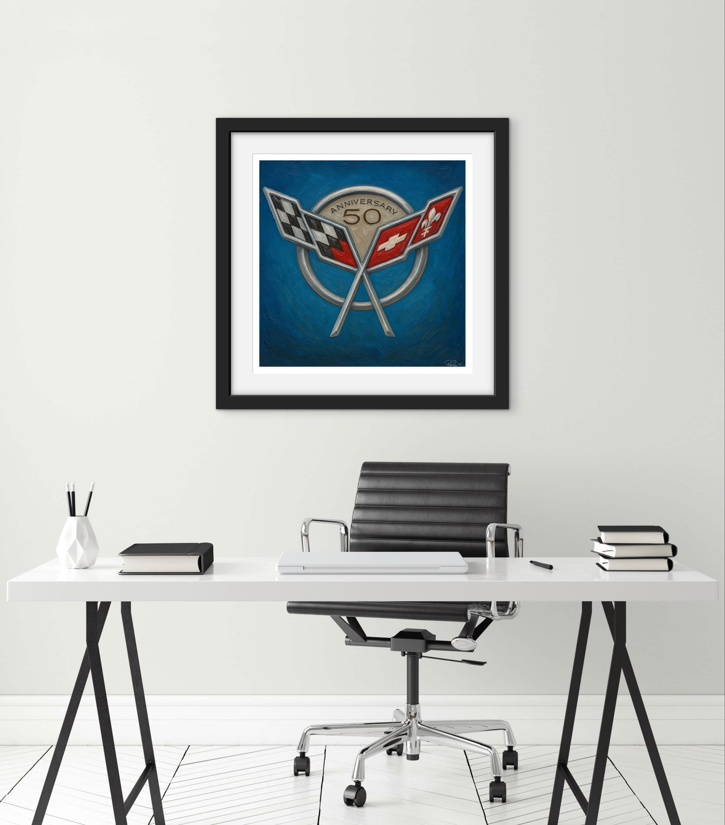 Framed artwork above a desk with office chair on a white wall