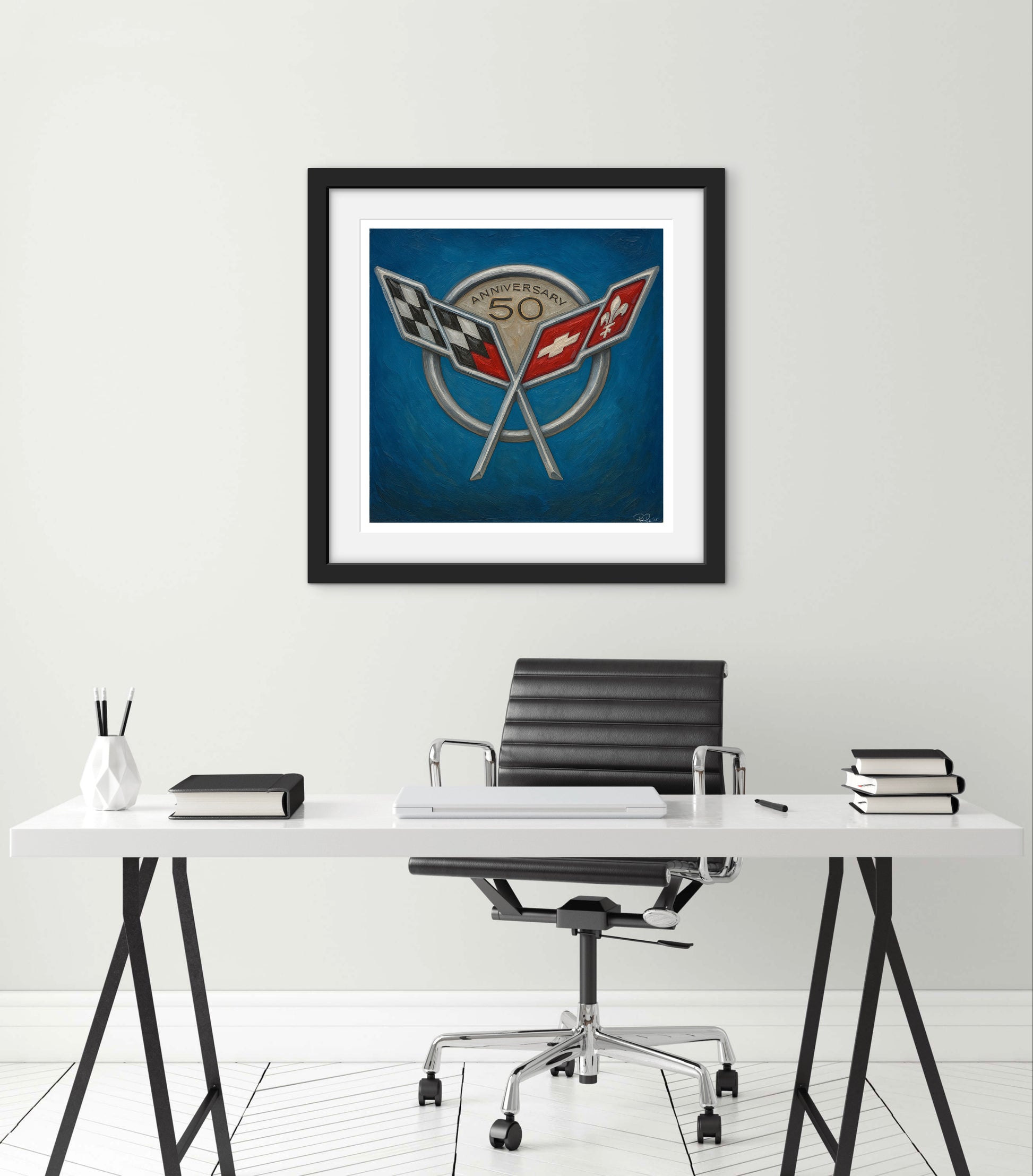 Framed artwork above a desk with office chair on a white wall