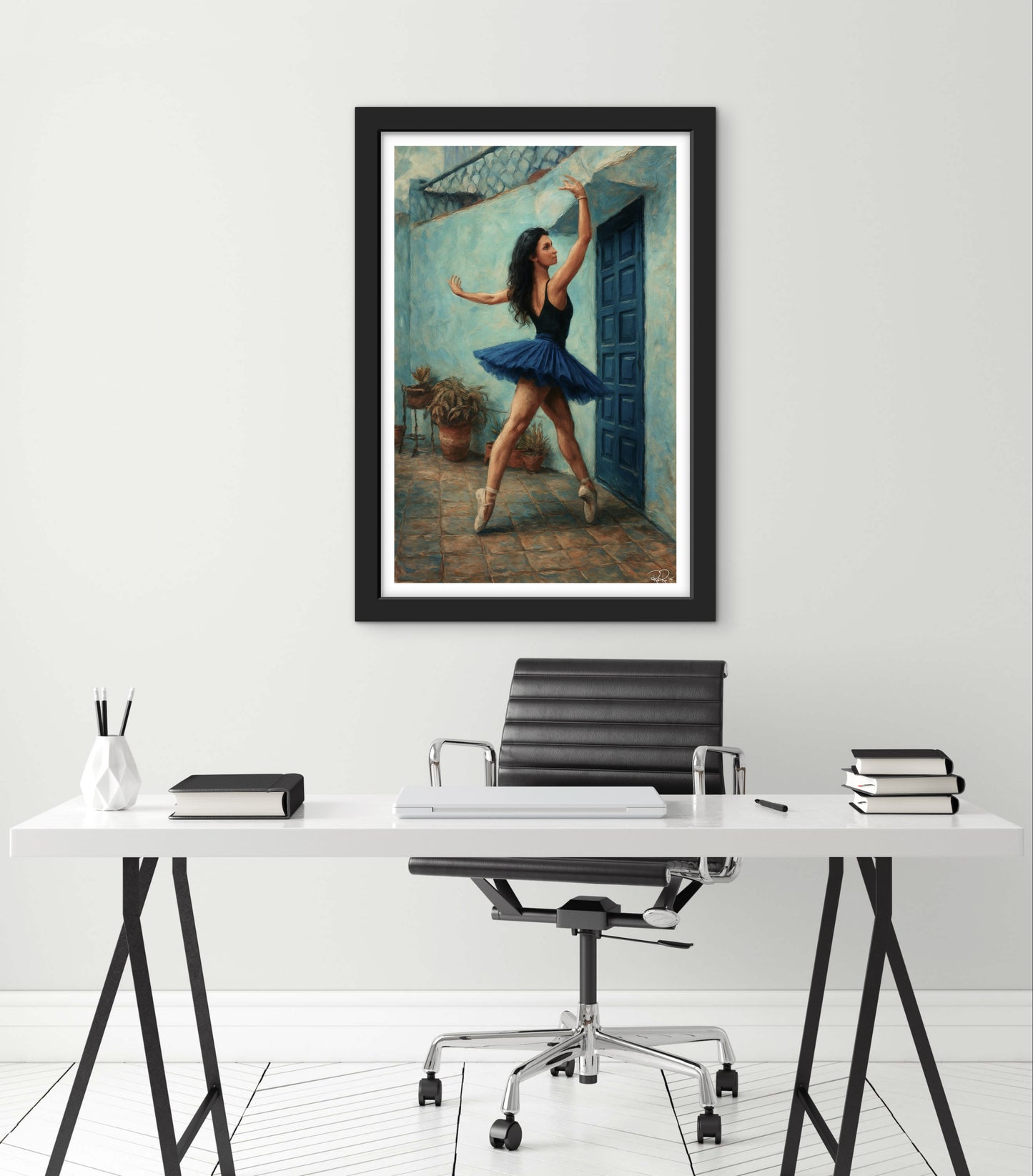 Framed artwork of a dancer in a blue dress on a white wall above a desk.