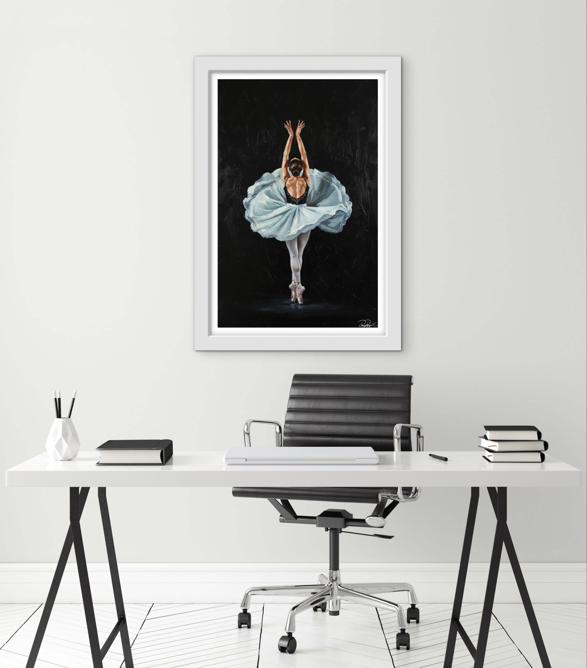 Framed artwork of a dancer in a blue dress on a white wall above a desk.