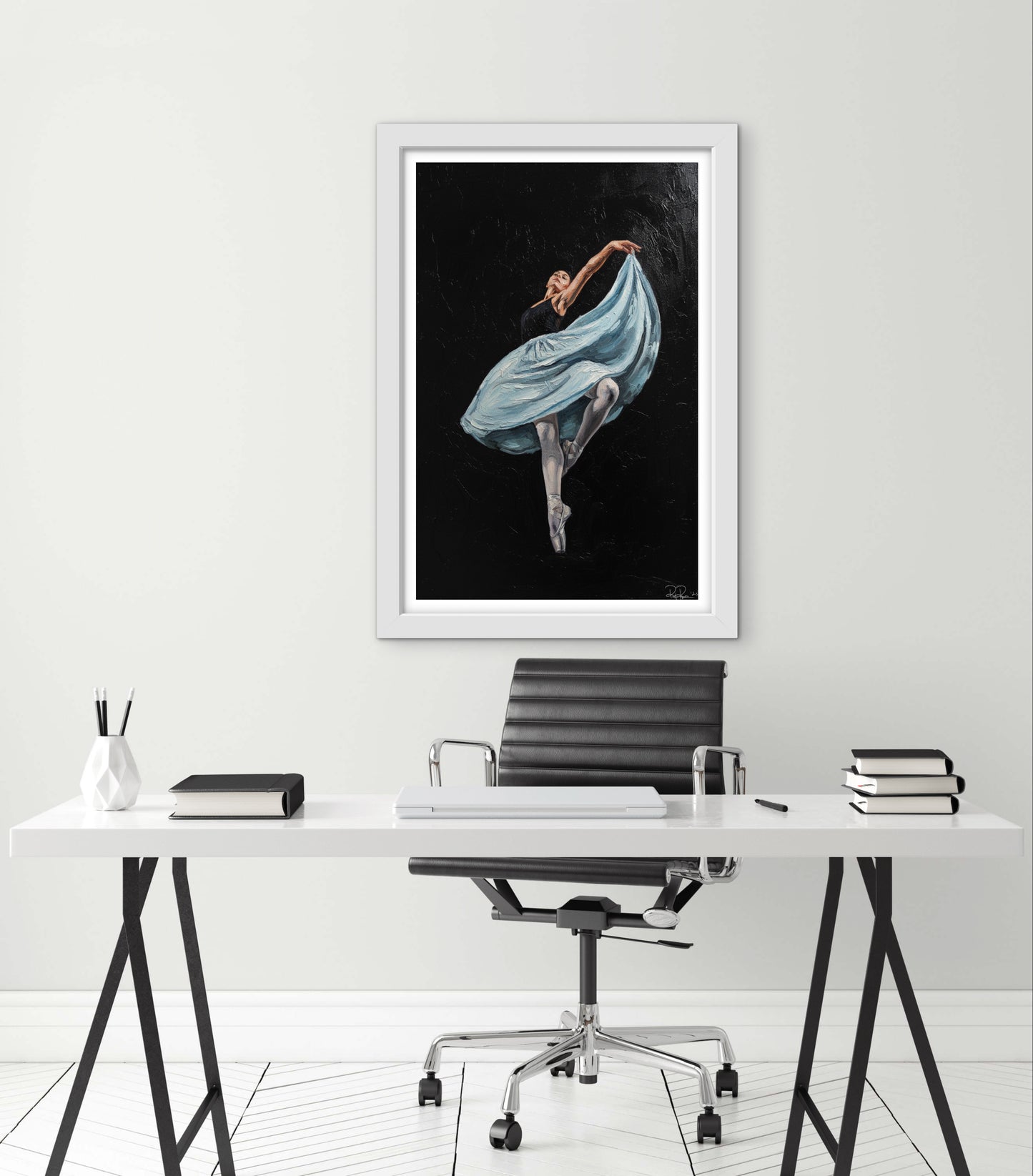 Framed artwork of a dancer in a blue dress on a white wall above a desk.