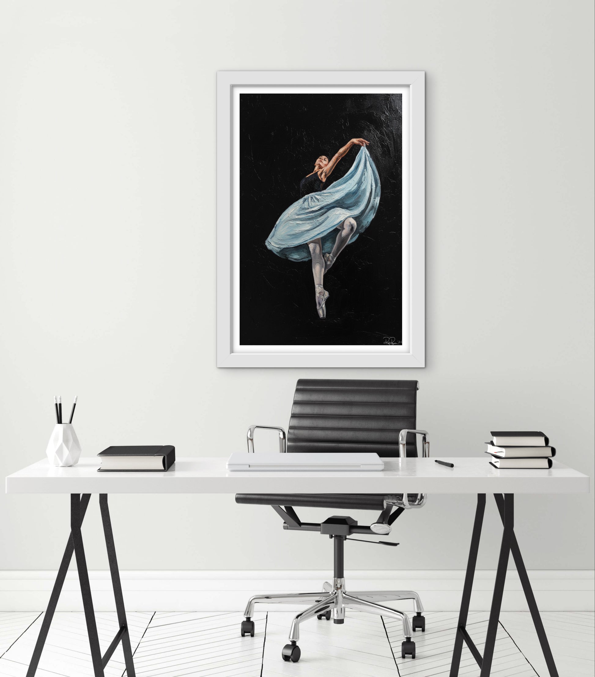 Framed artwork of a dancer in a blue dress on a white wall above a desk.