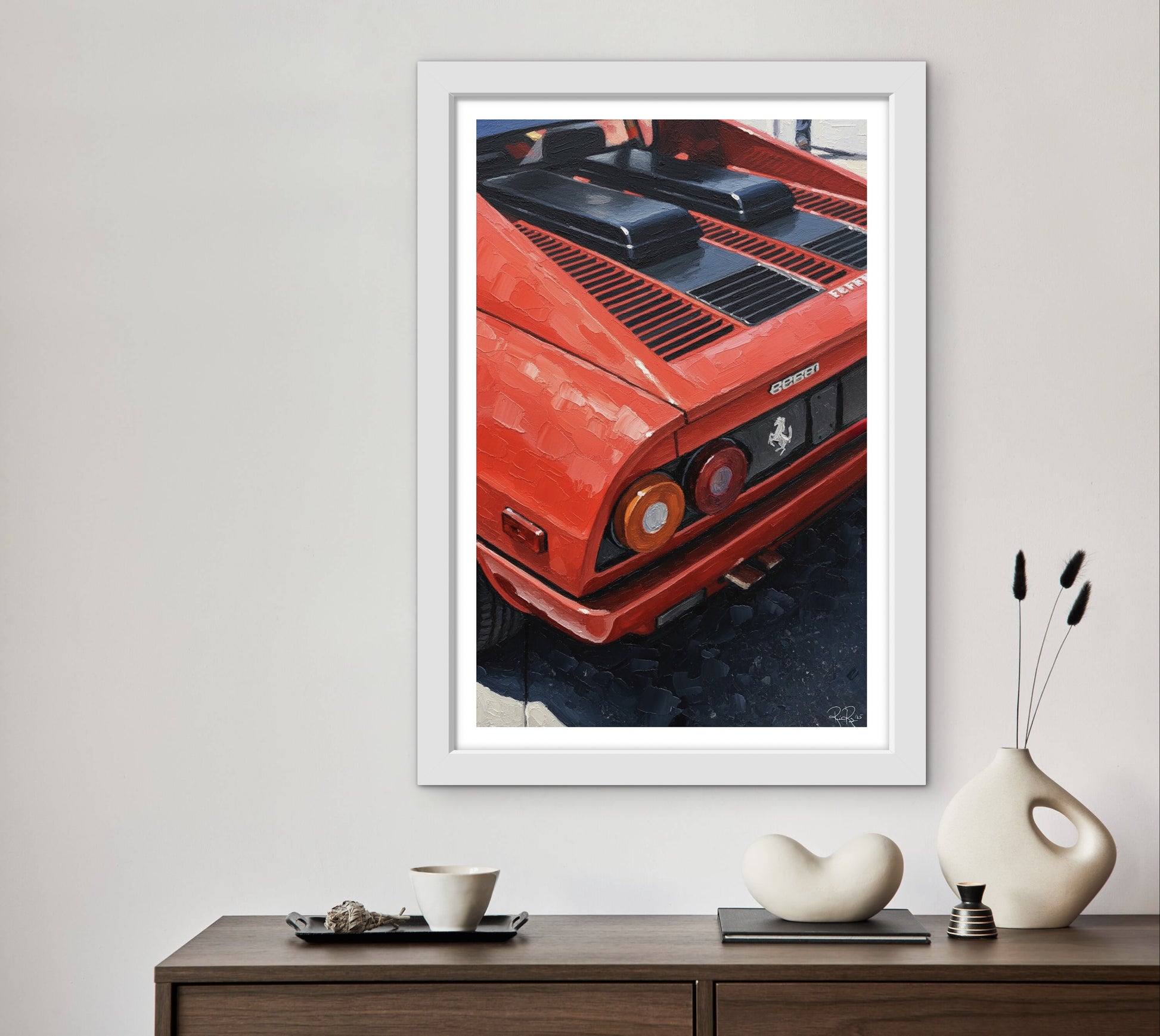 Framed picture of a red car on a wall above a wooden console table with decorative items.